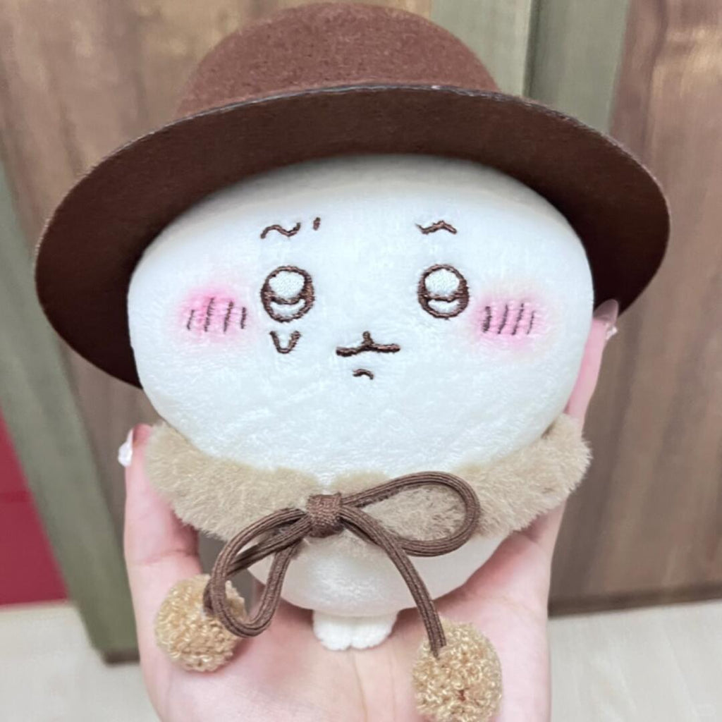 Chiikawa plush wearing a brown hat and ribbon cape
