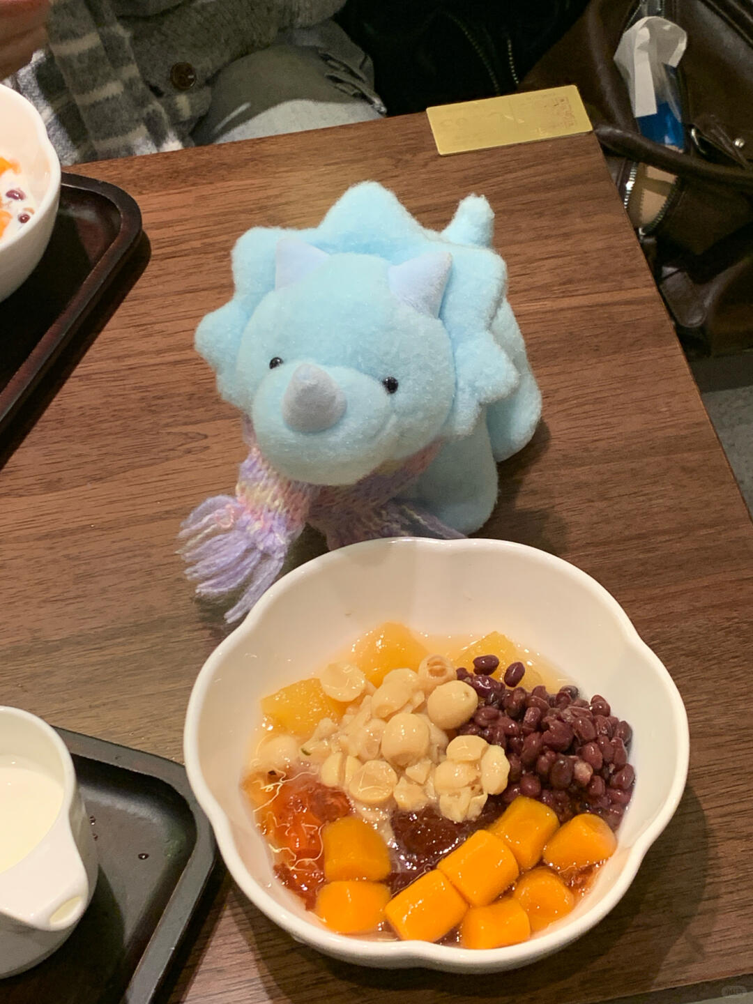 Bowl of dessert with a blue dinosaur plush toy on a wooden table