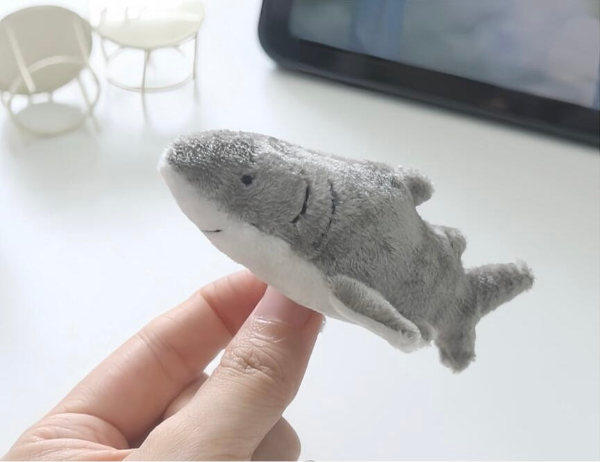 Plush shark toy held in a hand with a blurred background