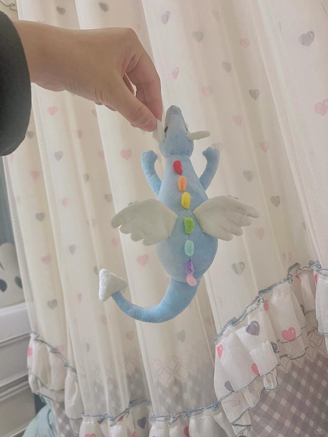 Small blue Sky Dragon plush sewing pattern sample held up to show wings, curved tail, and rainbow details