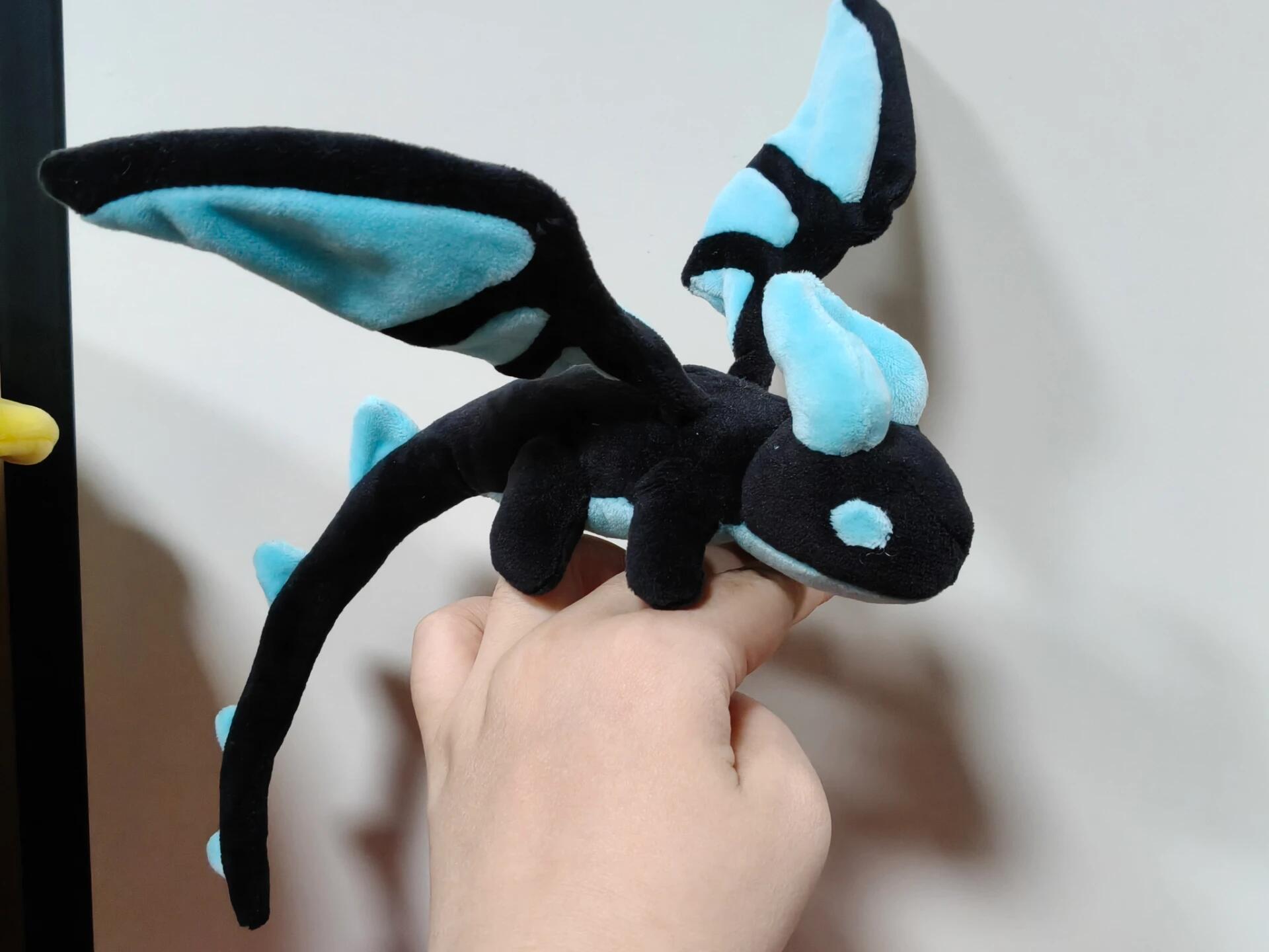 Plush dragon toy with black and blue colors held by a hand against a neutral background