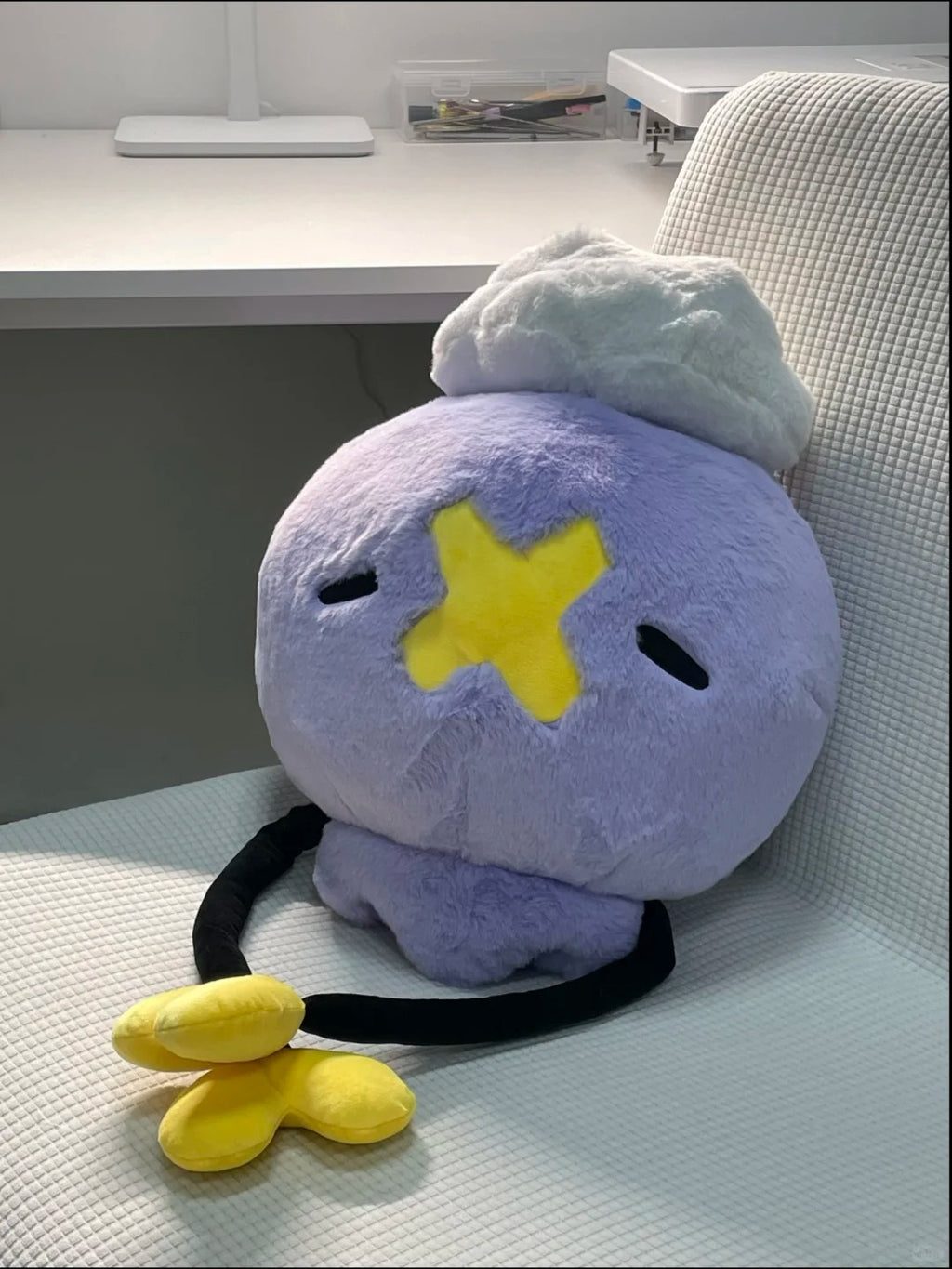 Large purple Drifloon plush with long black arms displayed on a chair