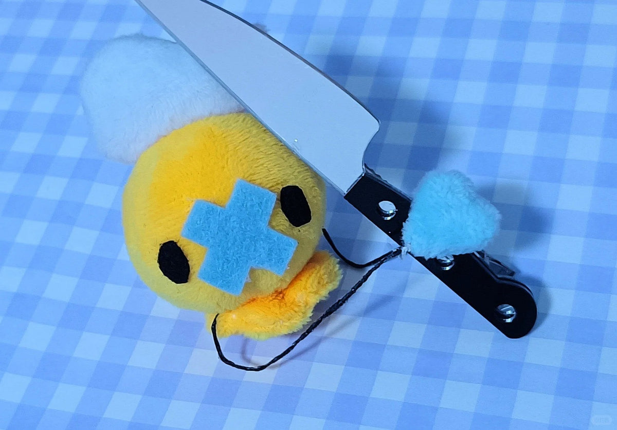 Yellow and blue Drifloon plush beside fabric scissors on a checkered work surface