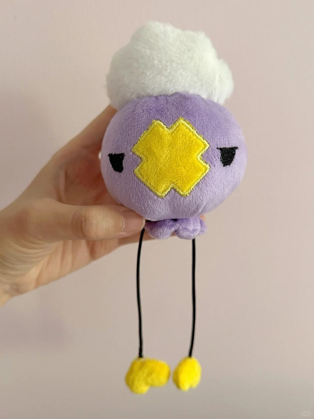 Front view of a small Drifloon plush sewing project held in one hand