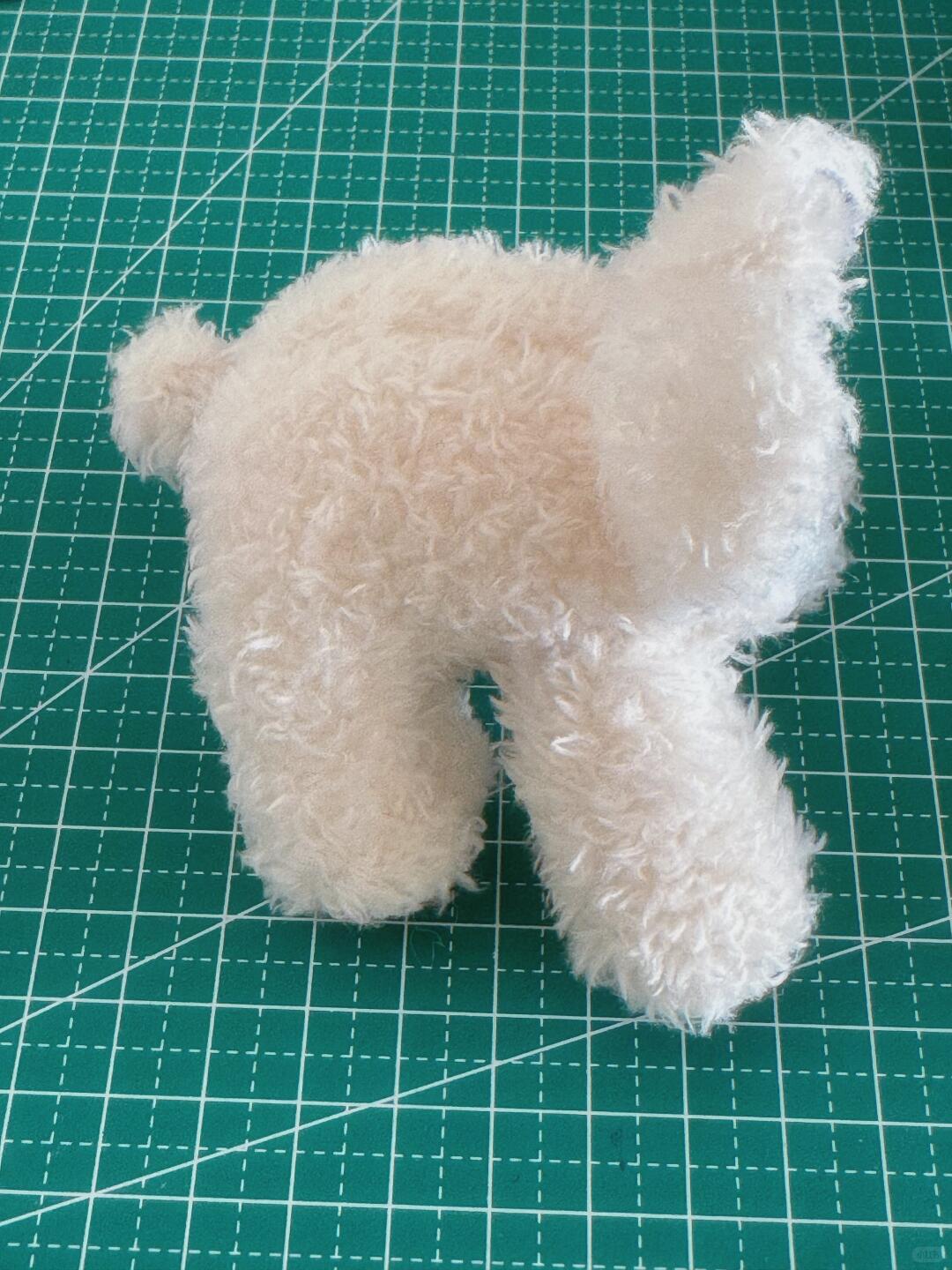White plush toy on a green cutting mat with grid lines