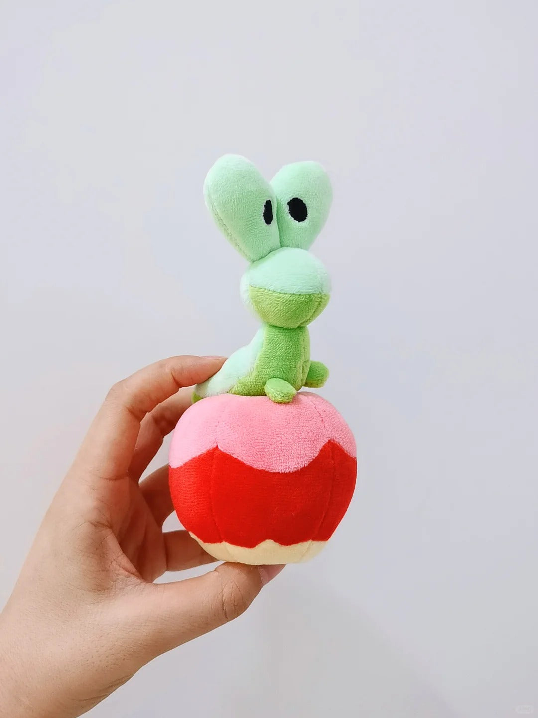 green Applin next to yellow apple plush, lifestyle photo with plant background