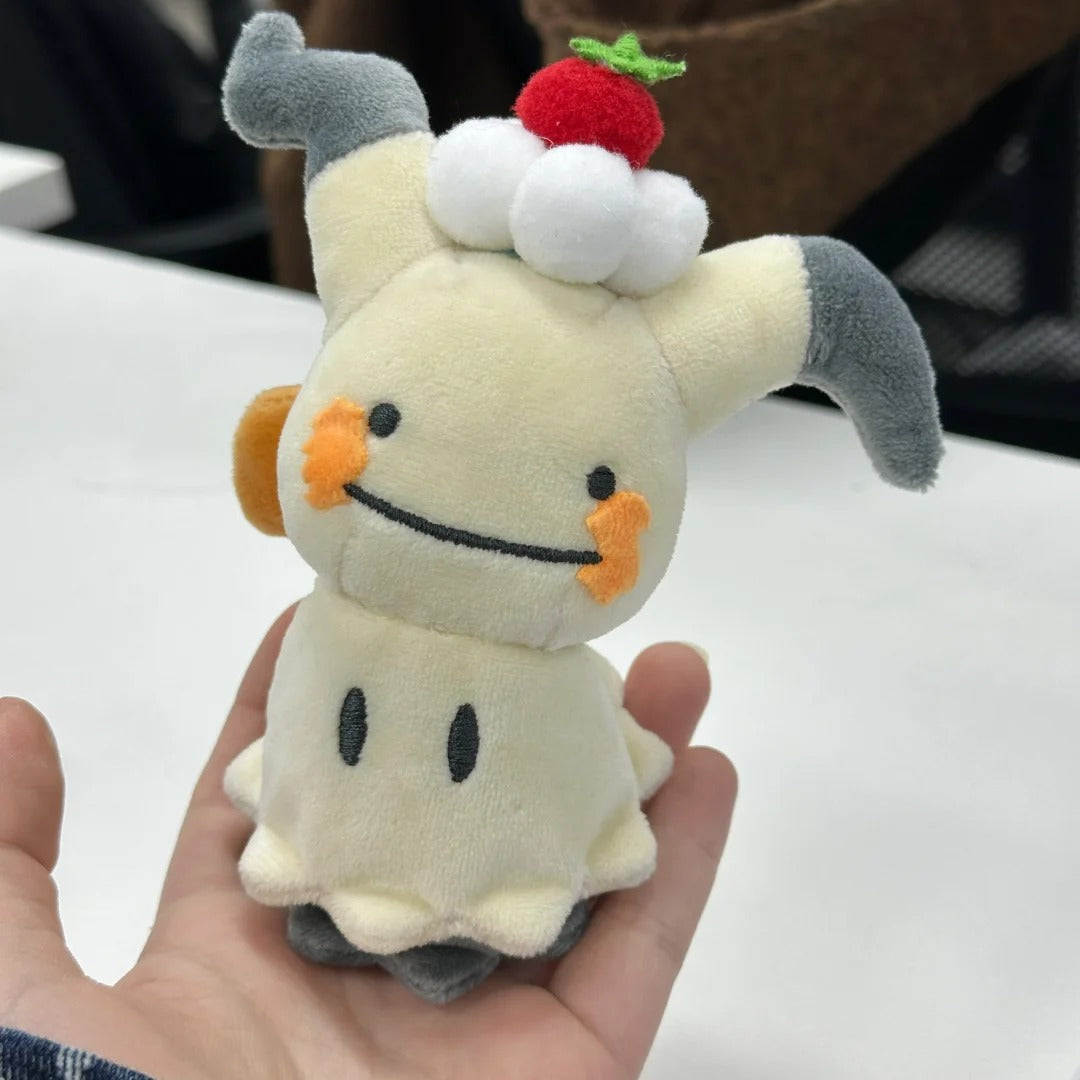 Mimikyu sewing pattern: Plush toy resembling a ghost with a strawberry on its head held in a hand against a blurred background