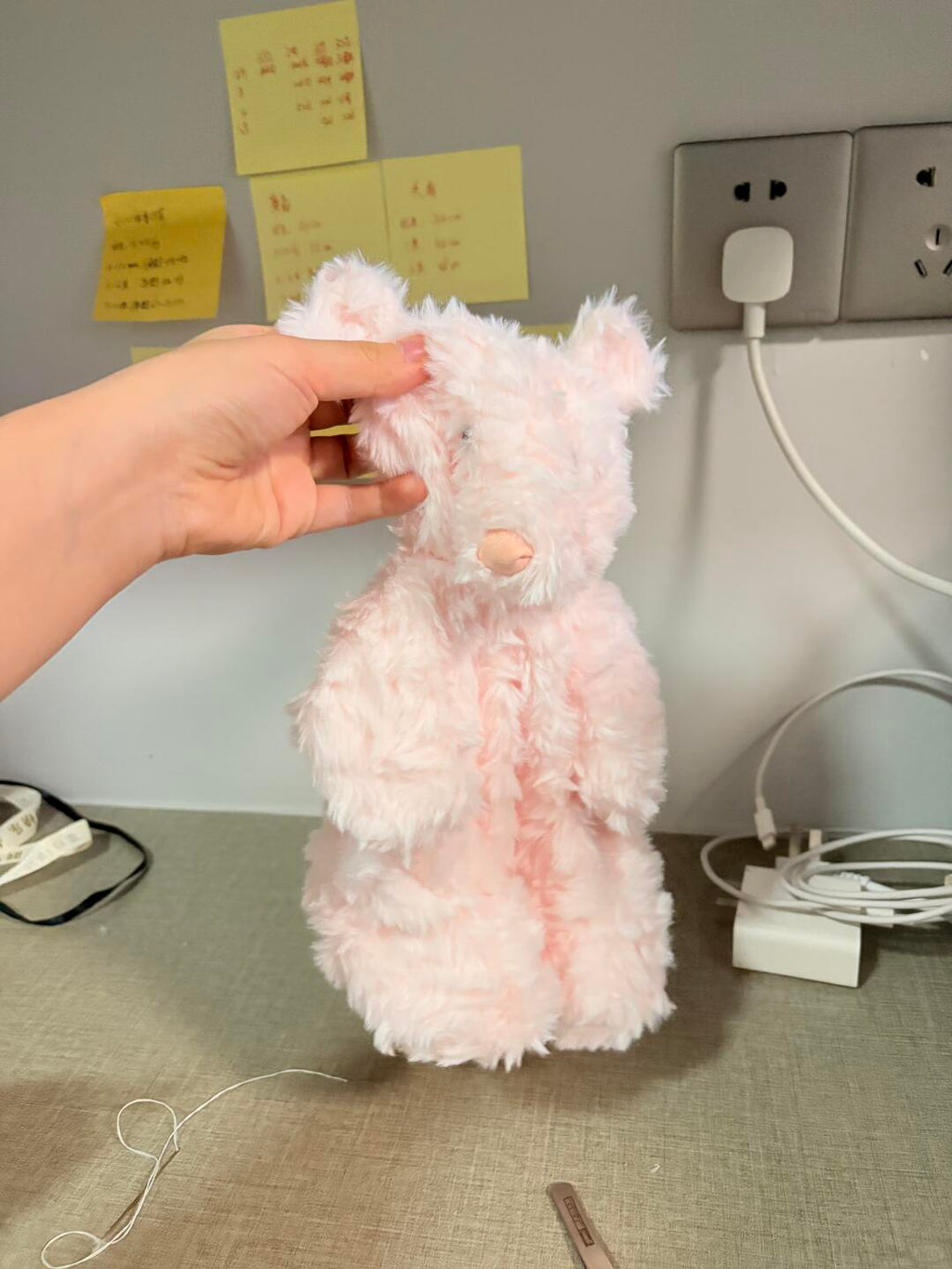 Jellycat teddy bear Pink fluffy toy held by a hand against a neutral background