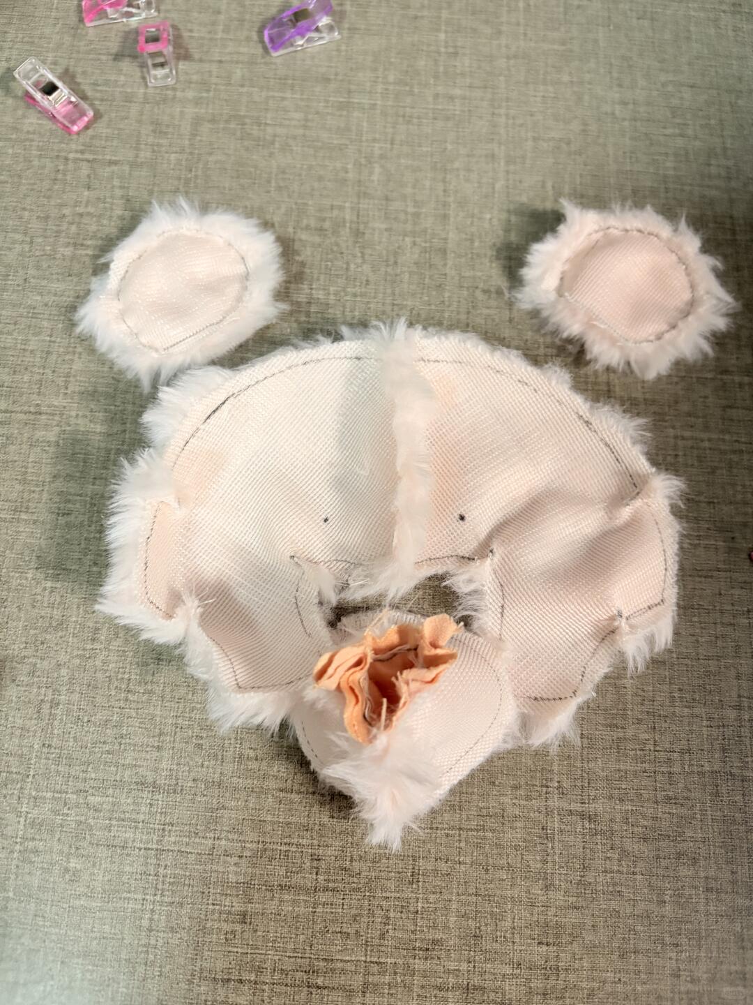 Jellycat Barcelona bear White plush toy with ears and a flower on a textured surface