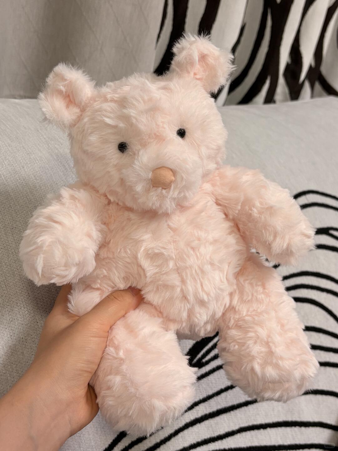 Handmade Jellycat Barcelona bear Pink teddy bear held by a hand on a zebra-patterned blanket