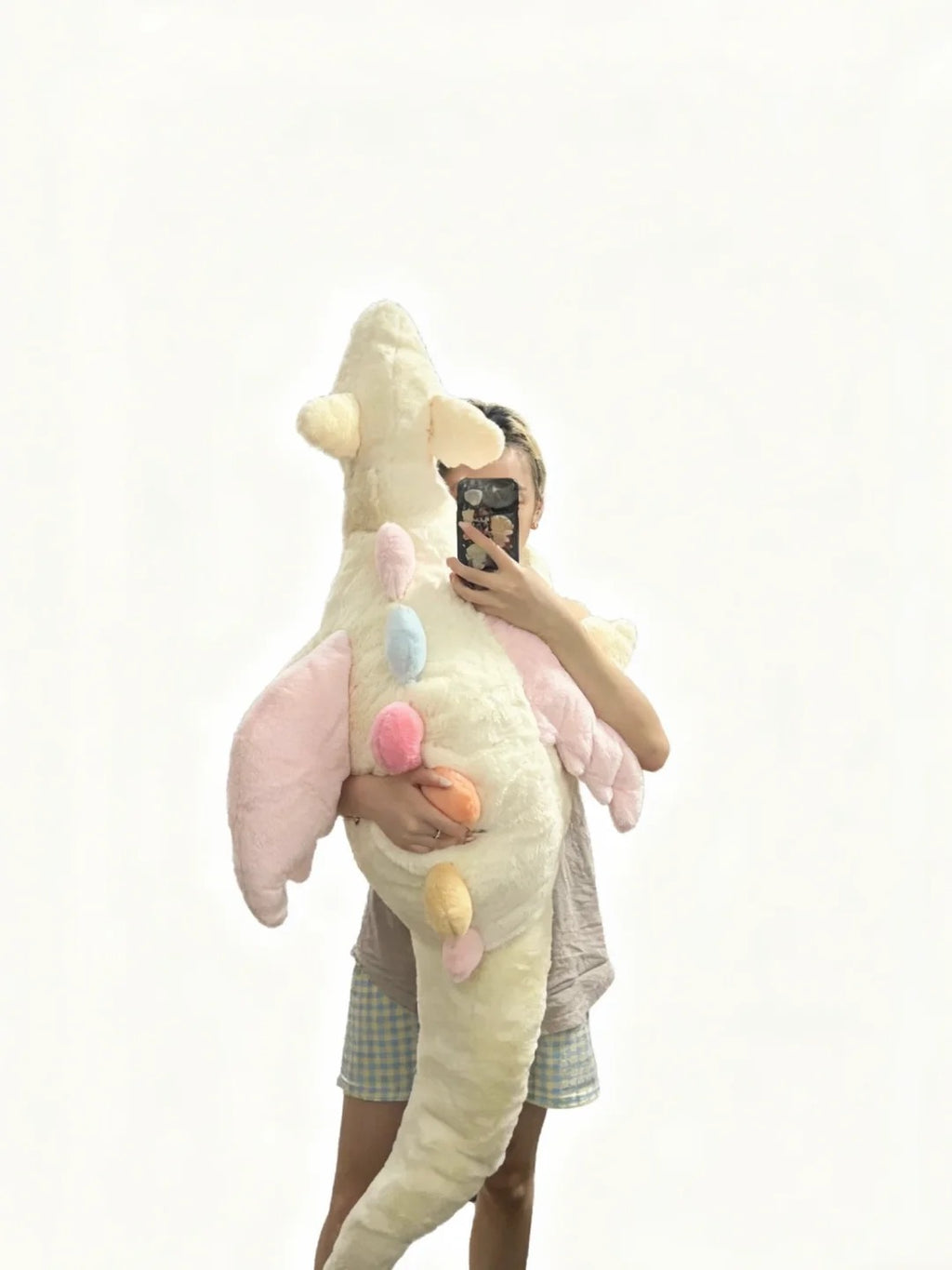 Person holding oversized cream Sky Dragon plush sewing pattern sample with pink wings and pastel spines