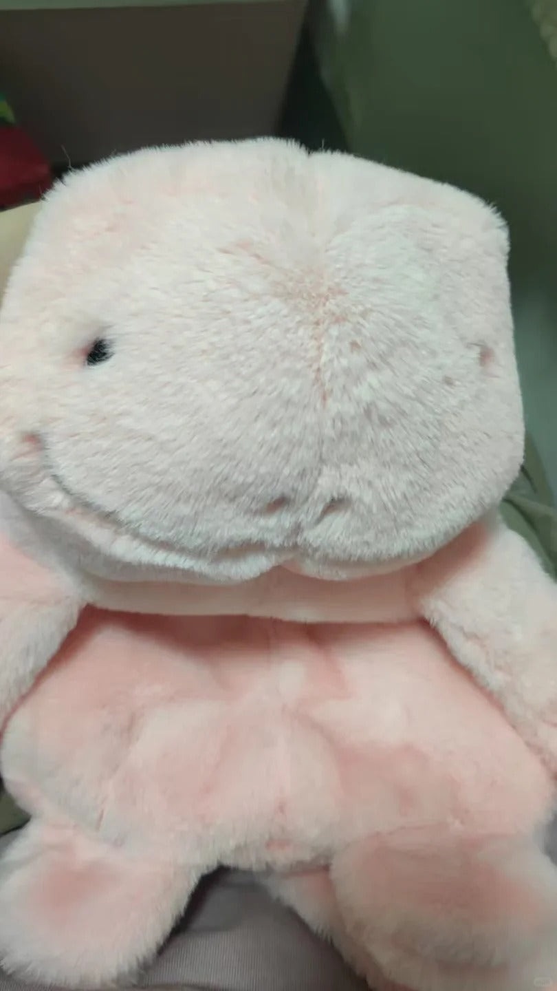 A close-up of a Quagsire plush stuffed animal in pale pink and white, showing soft fuzzy fabric and a small black embroidered eye.