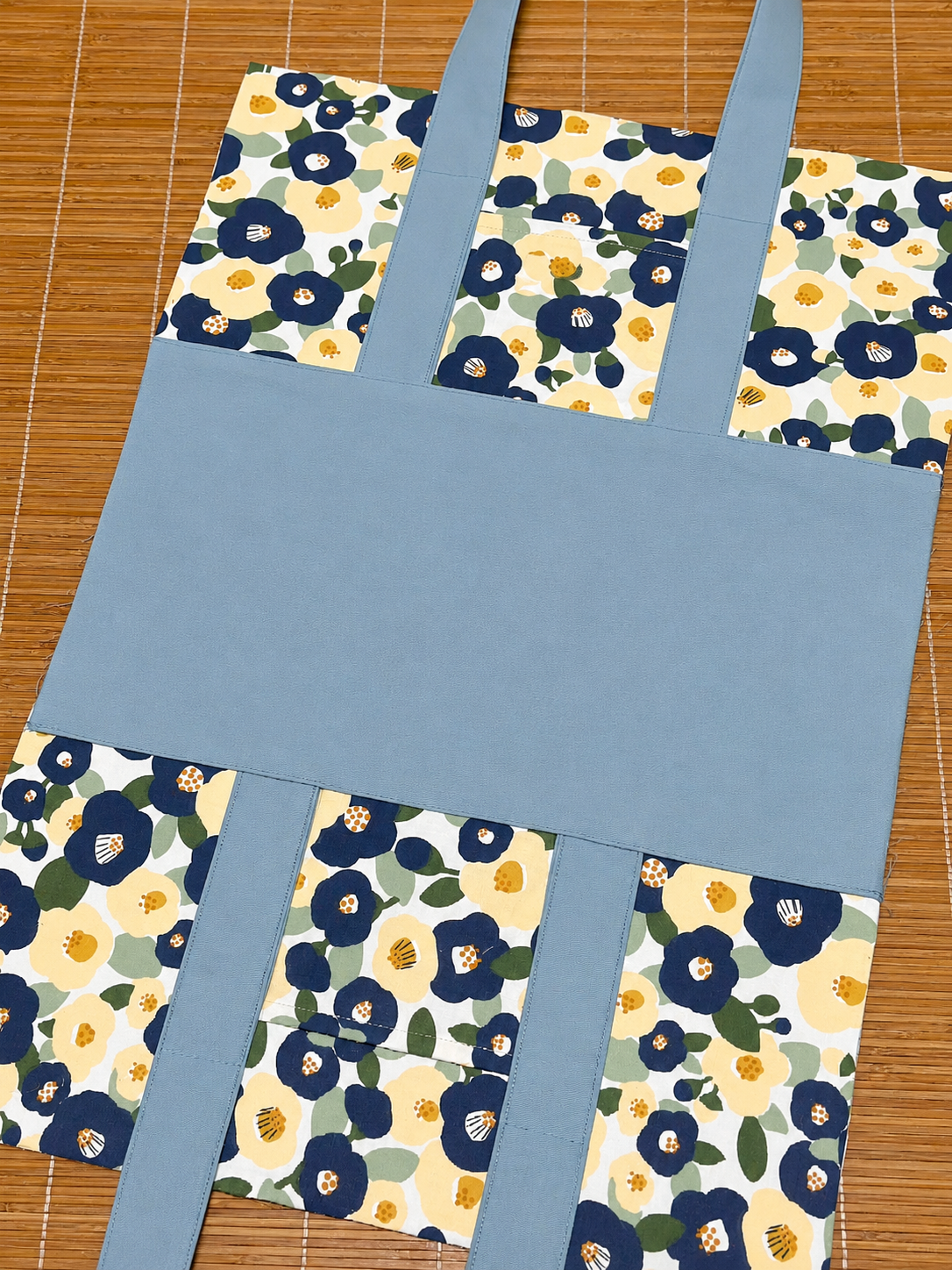 Blue tote bag with floral patterns on a wooden surface