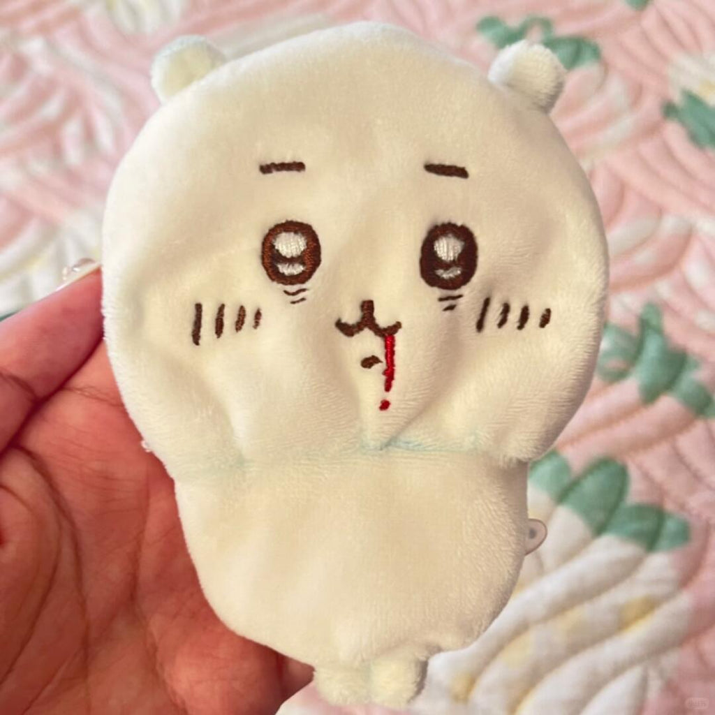 Cream Chiikawa plush with embroidered face held over bedding