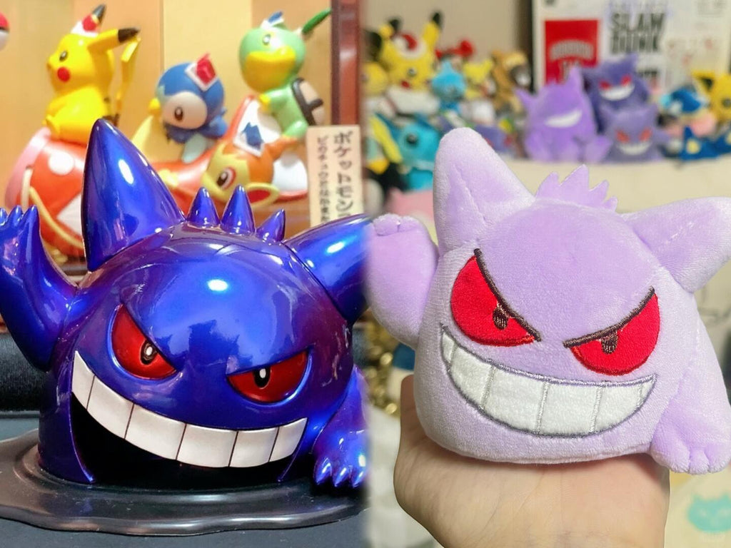 A hand holds a small purple Gengar plush toy next to a glossy blue-purple Gengar figurine with red eyes, with other Pokémon figures blurred in the background.