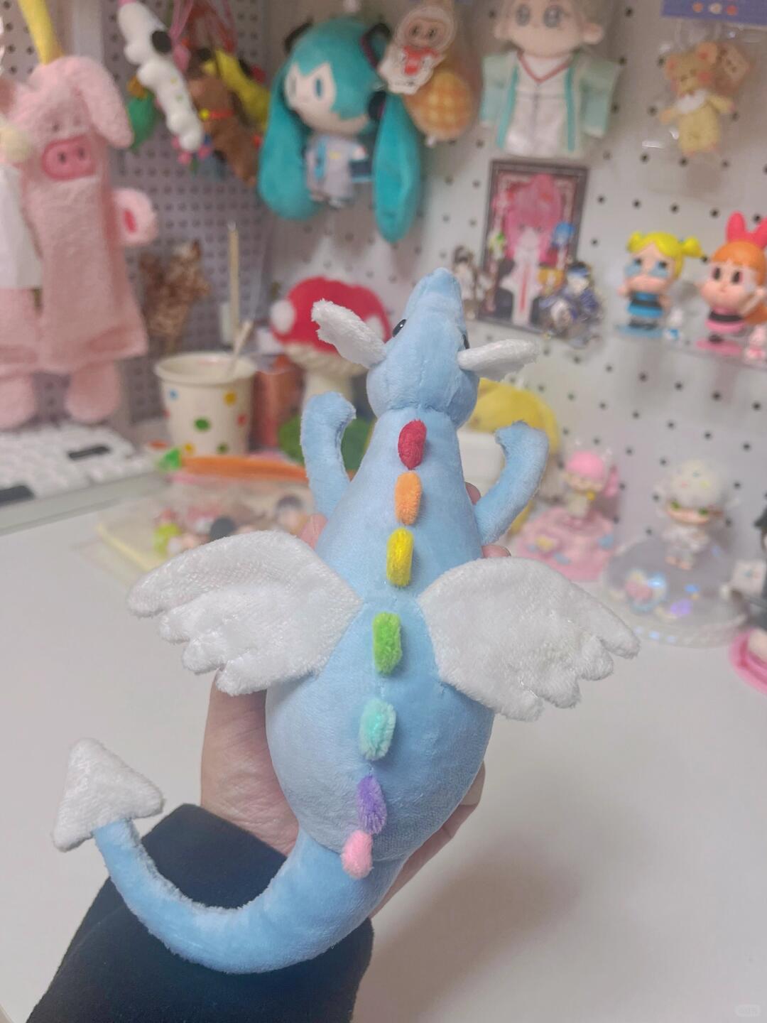 Back view of blue Sky Dragon plush sewing pattern sample with white wings and rainbow spines