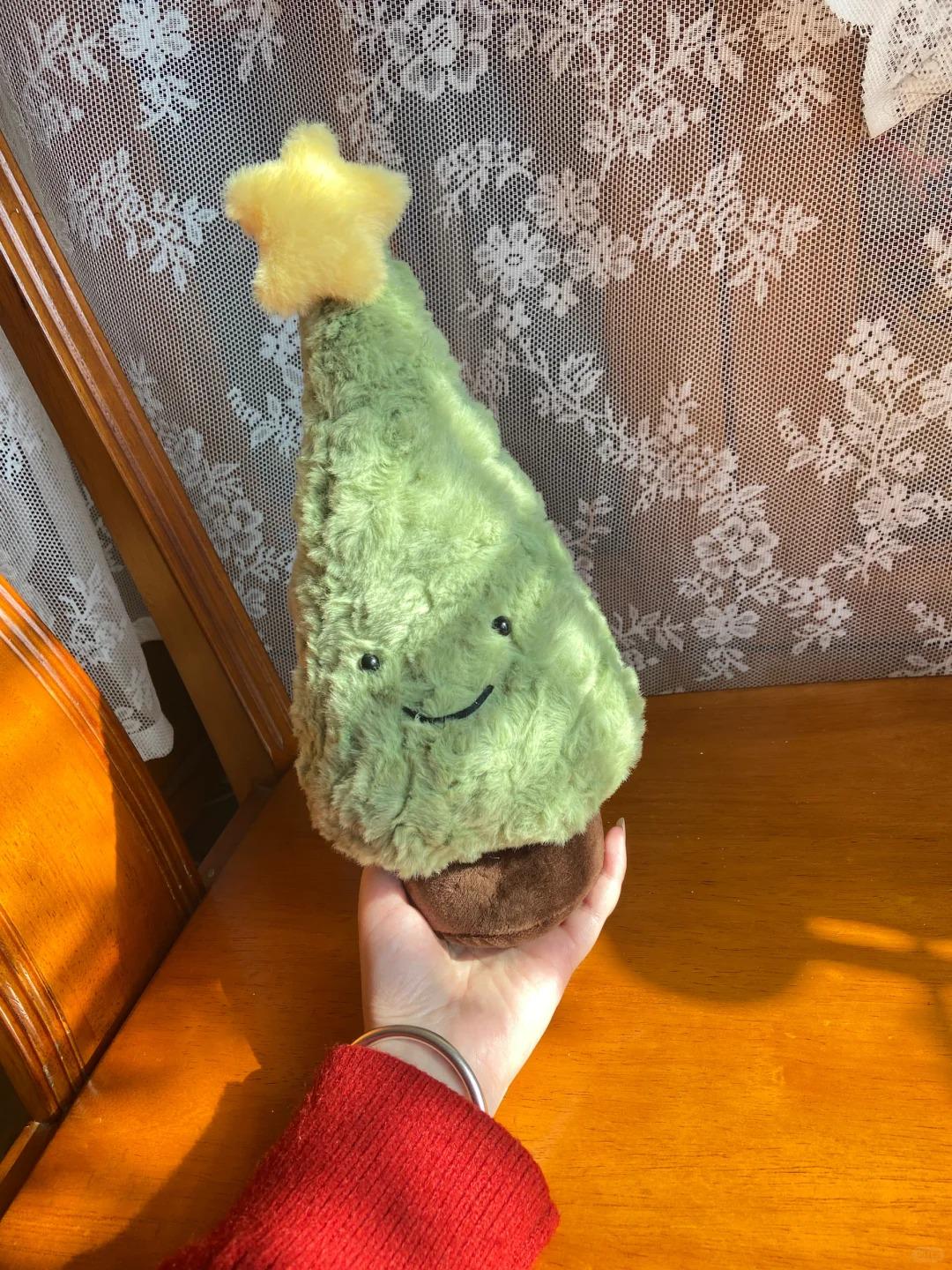 Plush toy shaped like a Christmas tree with a star on top, held by a person wearing a red sleeve.