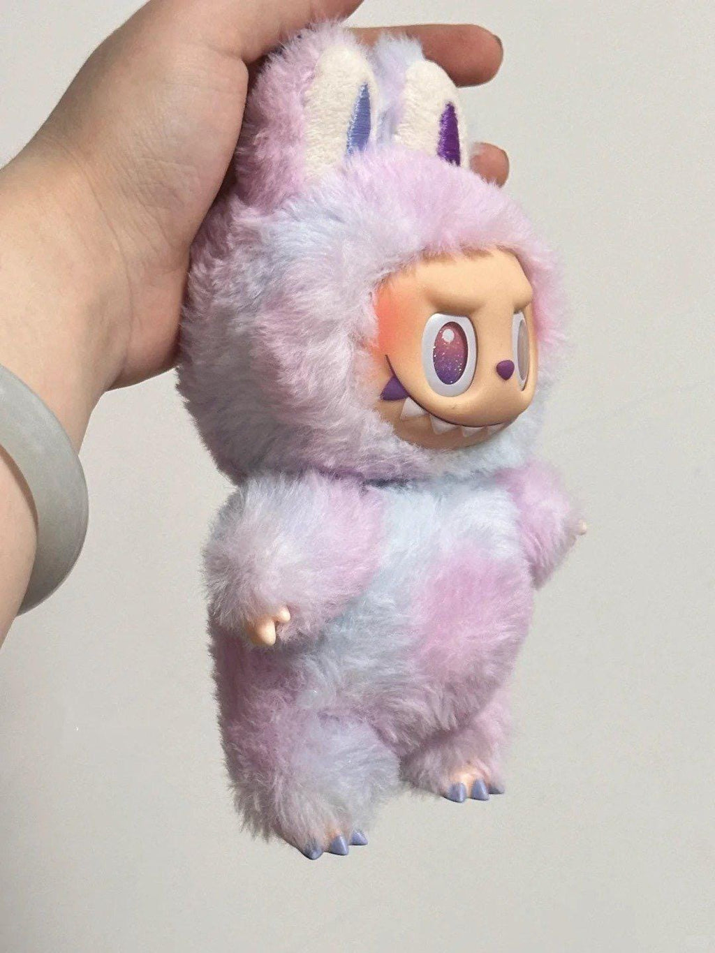 Labubu Plush toy with a cute design held by a hand against a plain background