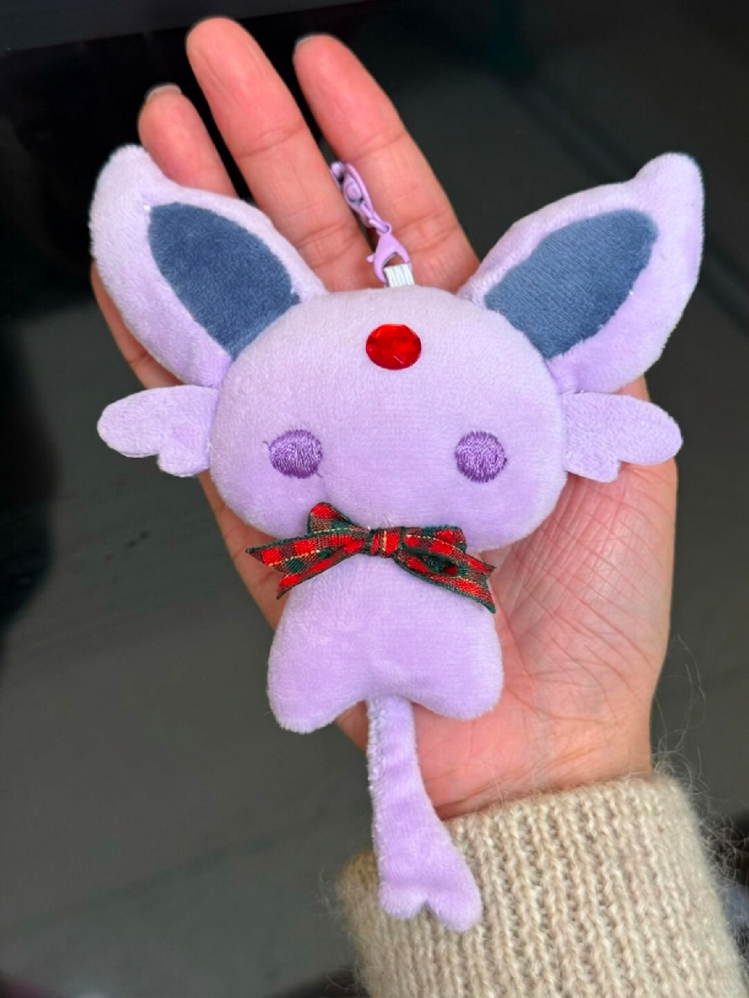 Eevee Espeon Plush keychain shaped like a cartoon character with purple body and blue ears held in a hand.