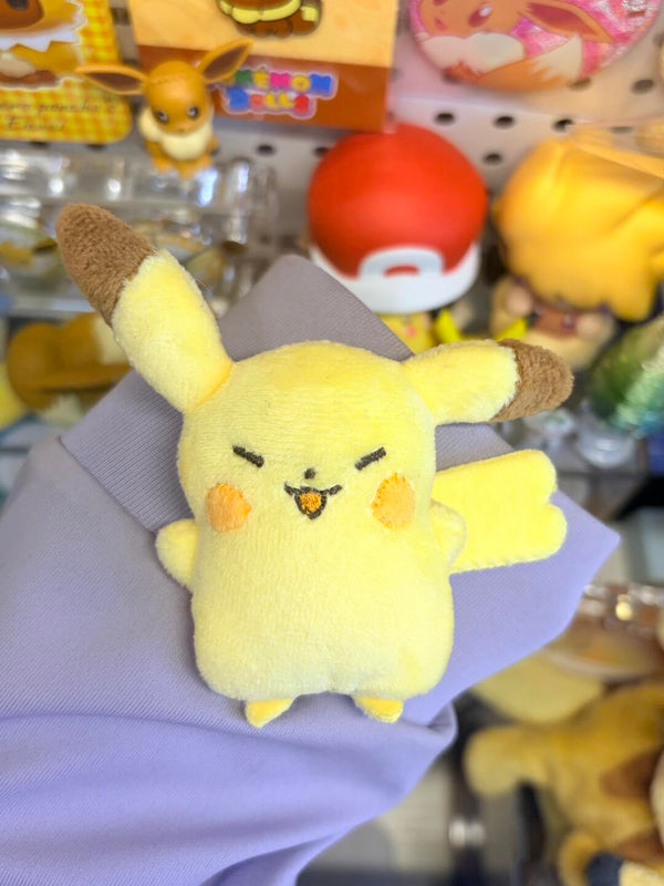 Plush toy resembling Pikachu held by a gloved hand with a store display in the background.