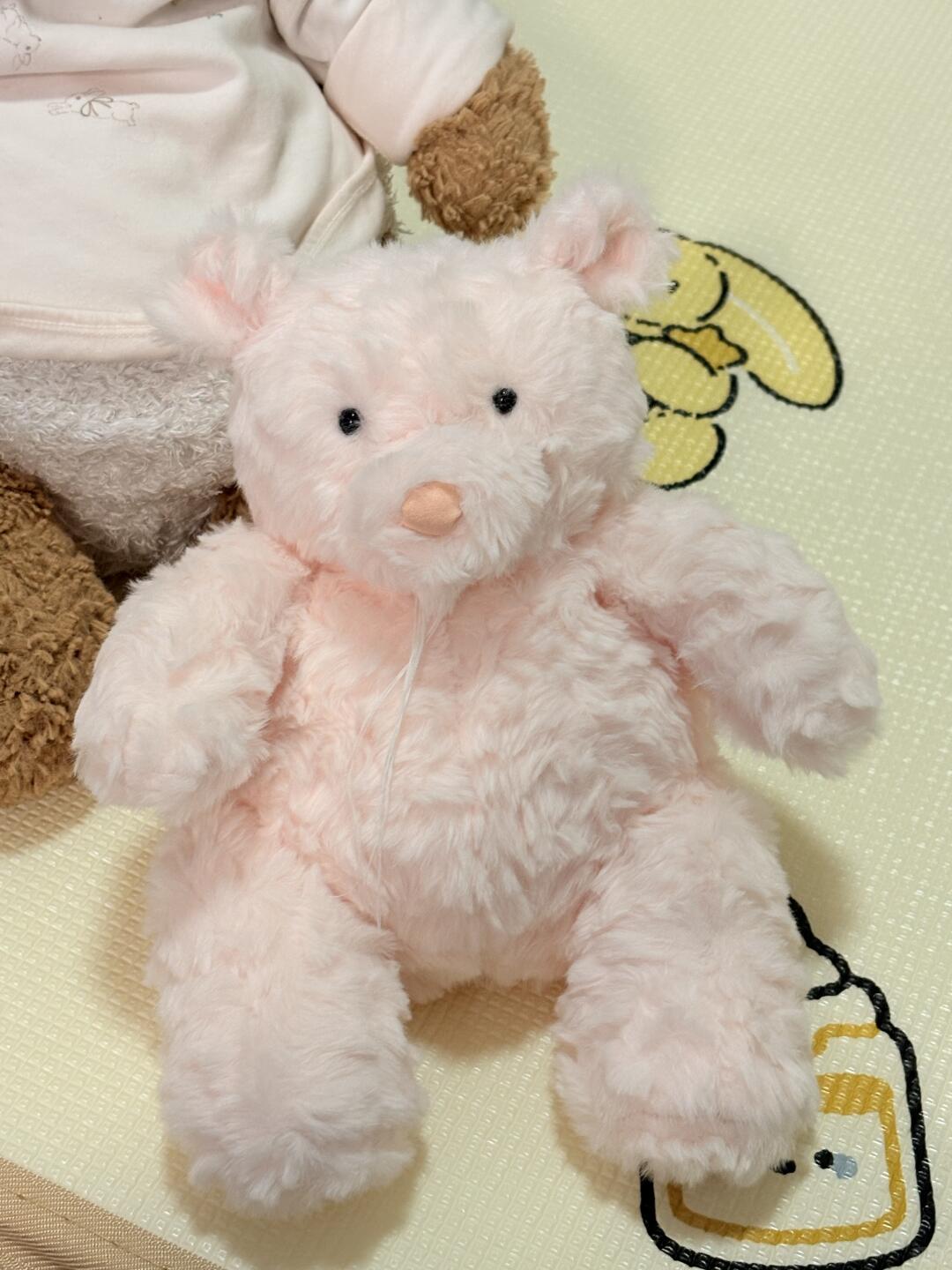 Pink plush toy on a yellow blanket with cartoon designs