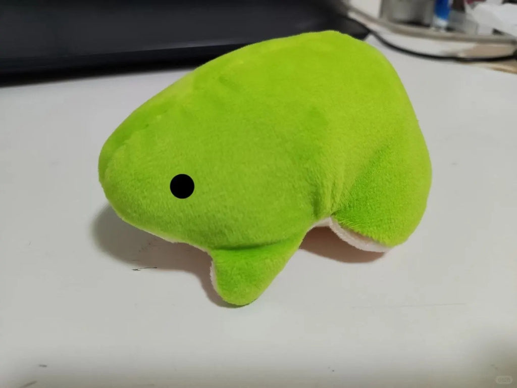 Side view of a bright green frog plush with a white belly and a small black eye.