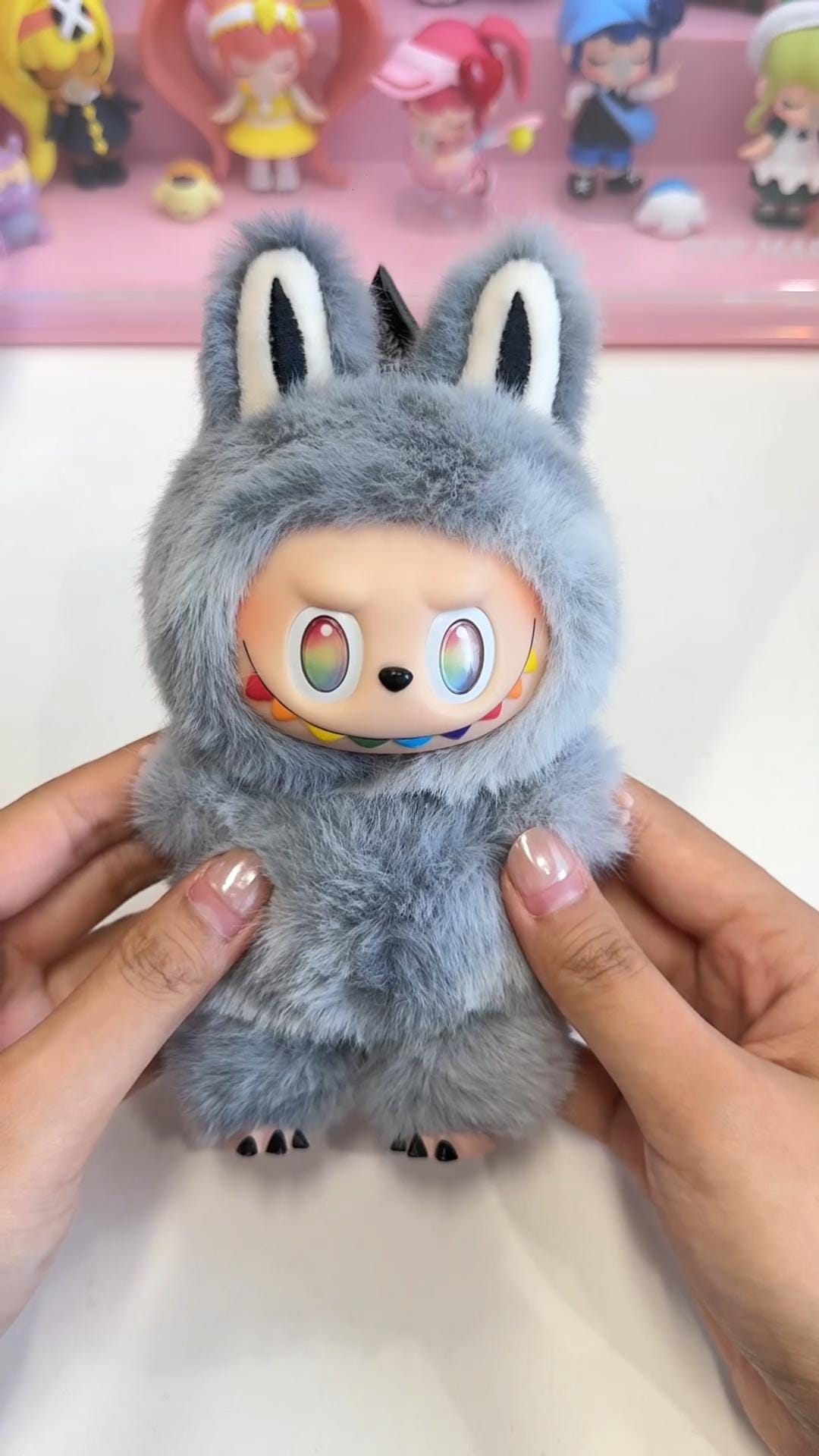 Labubu Plush toy with colorful face held by hands against a blurred background