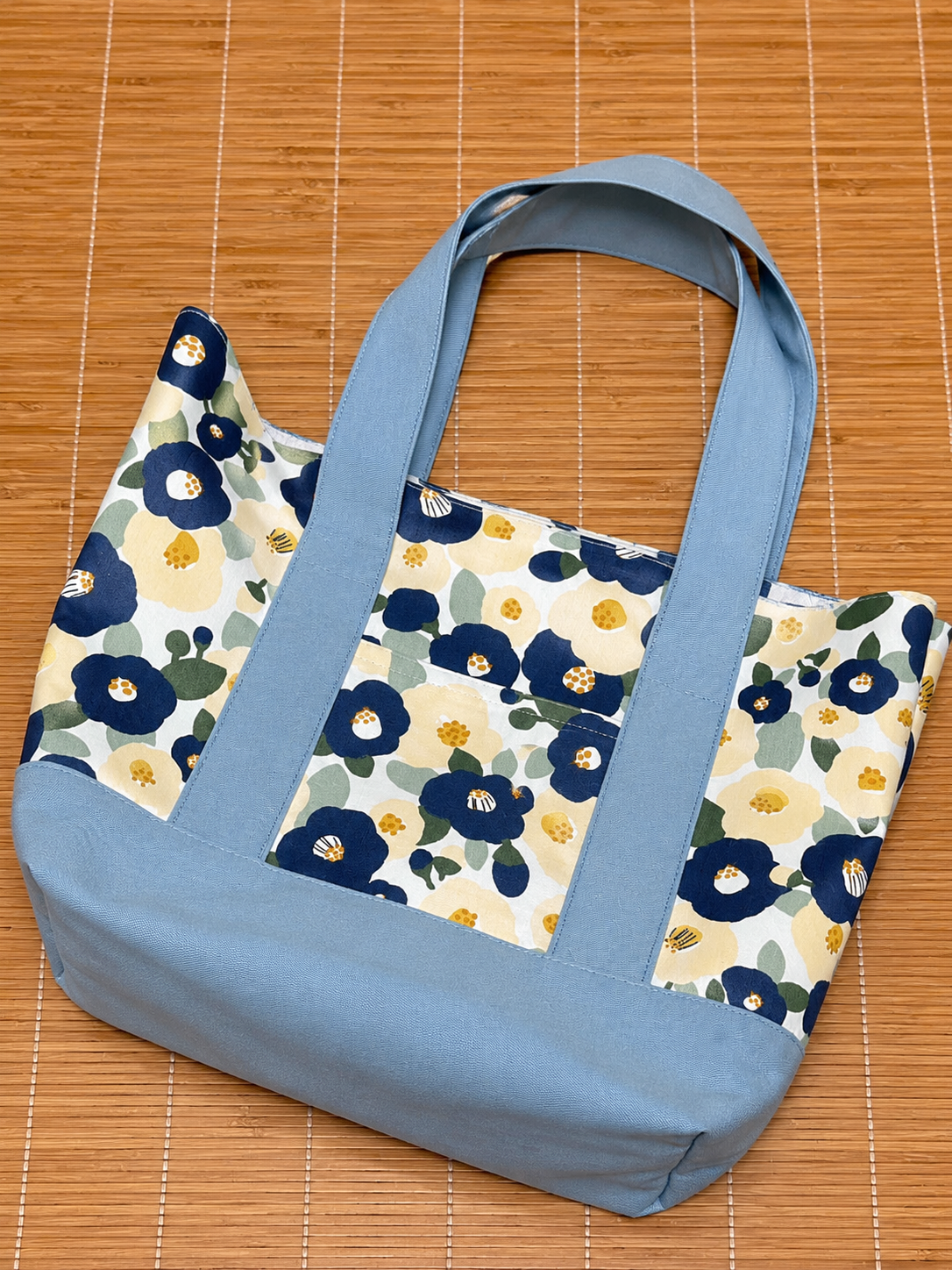 Floral-patterned bag with blue straps on a wooden surface