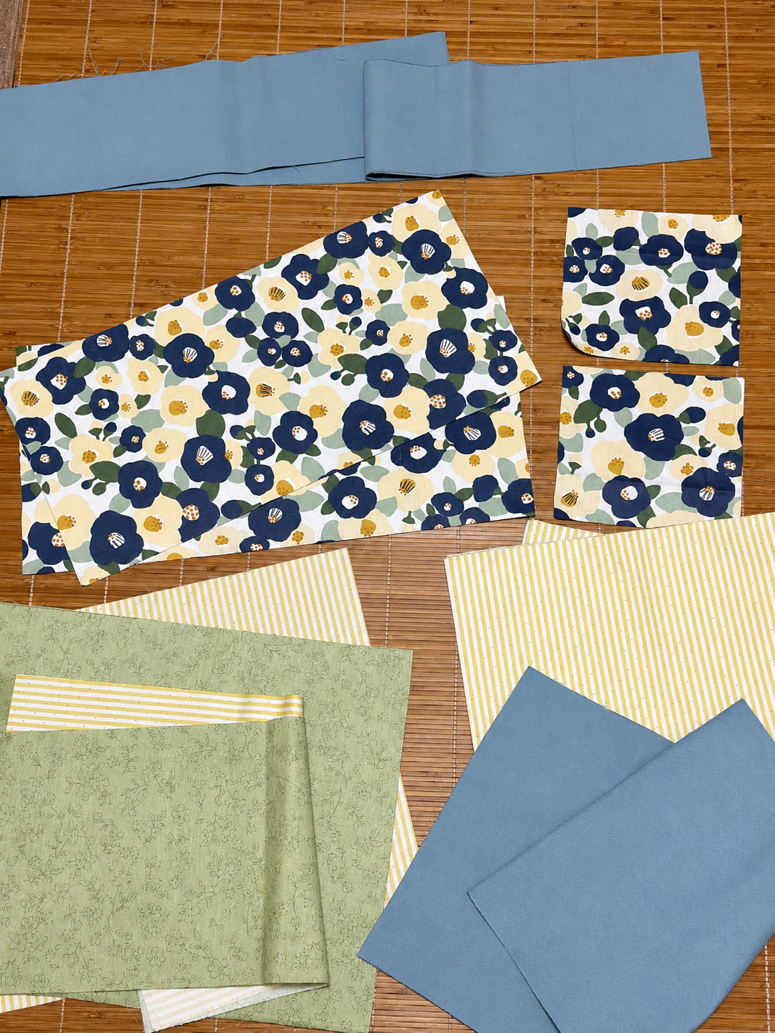 Collection of fabric samples with floral and solid patterns on a wooden surface
