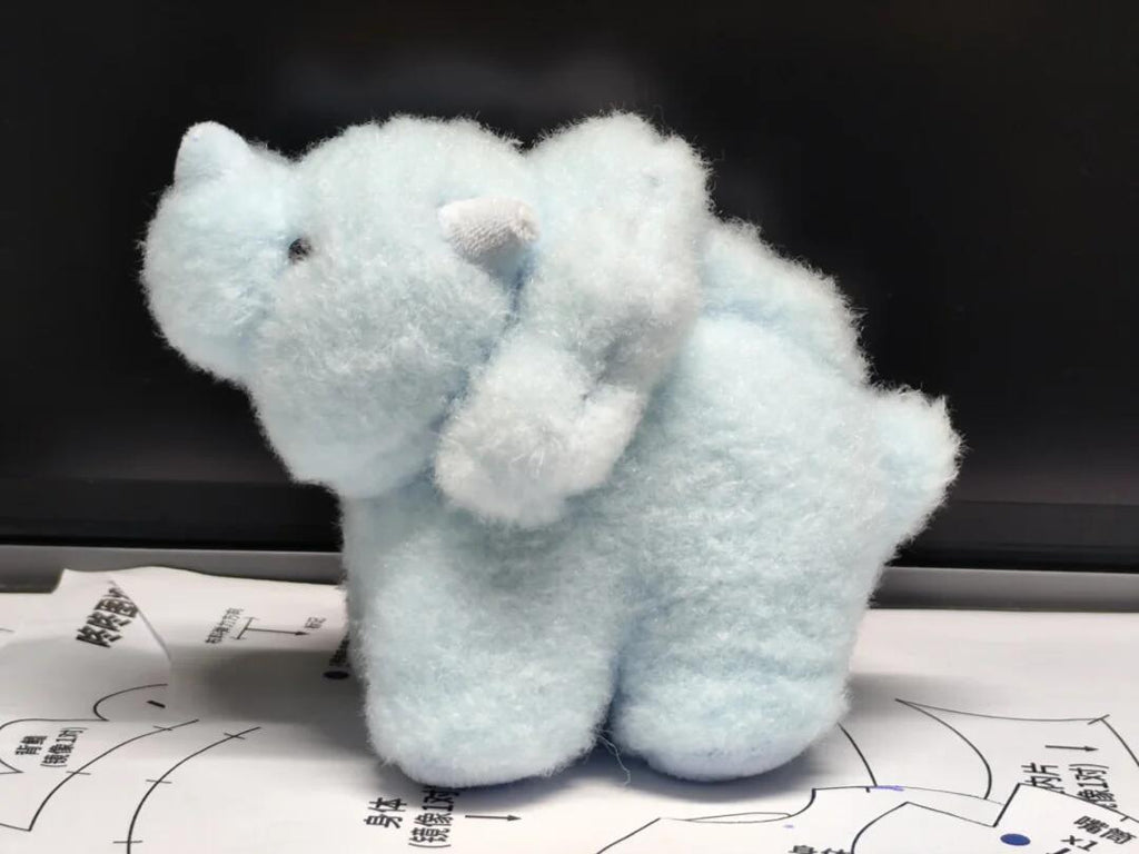 Light blue plush toy dinosaur on a dark background