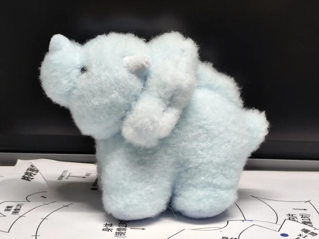 Light blue plush toy dinosaur on a dark background