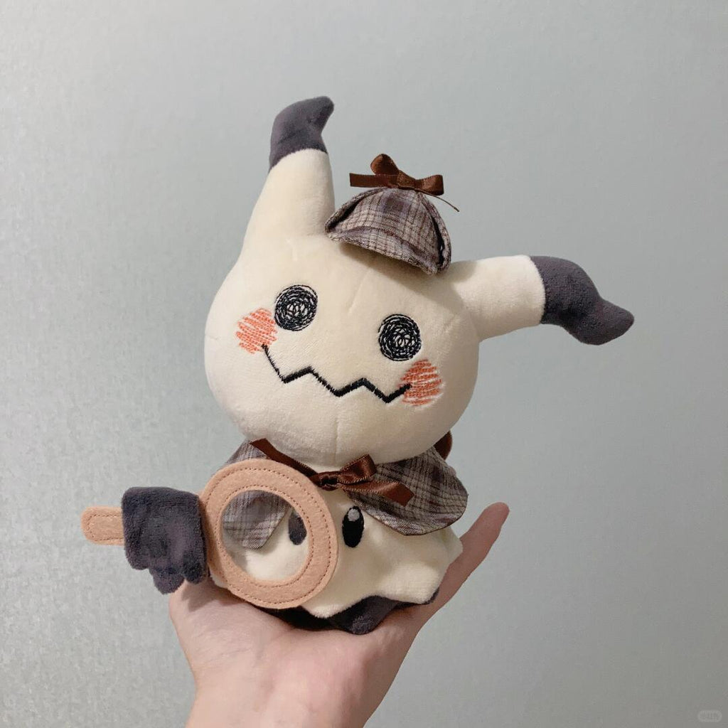 Mimikyu Plush toy resembling a detective cat held in a hand against a gray background