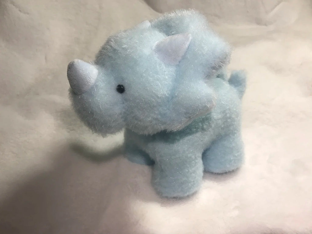 Small blue plush rhino toy on a light beige surface