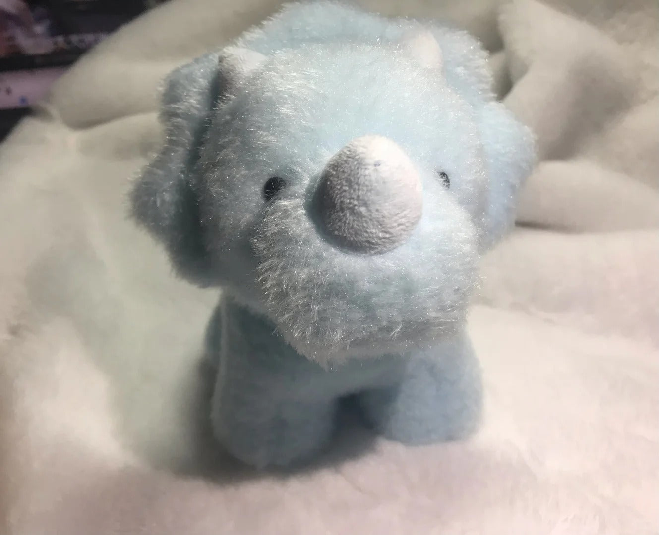 Blue plush toy dinosaur on a beige surface