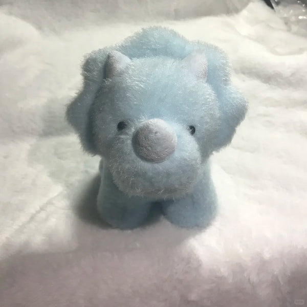 Blue dinosaur plush toy on a white blanket