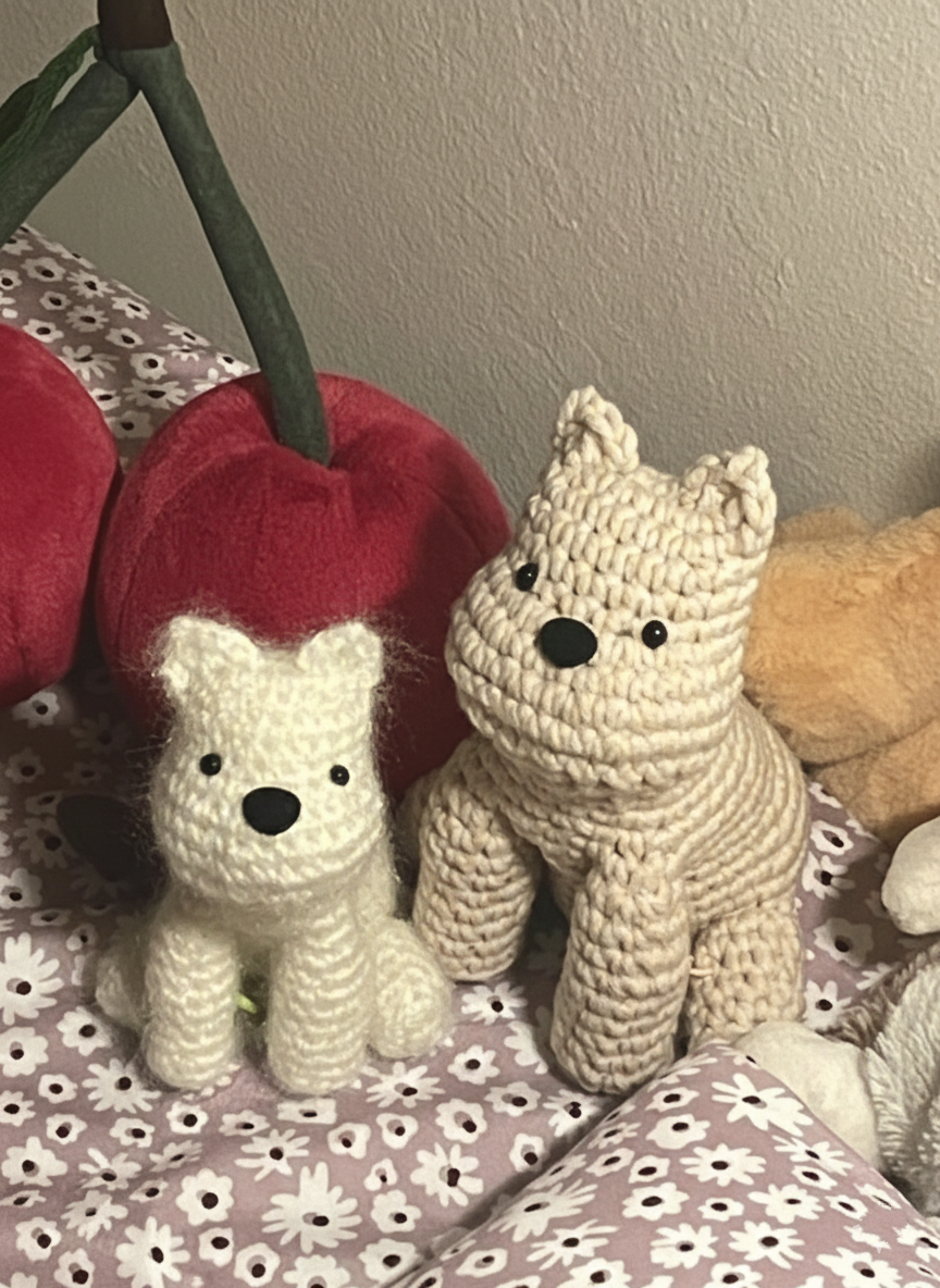 Two knitted crochet dog toys on a floral-patterned surface with a plain wall in the background.