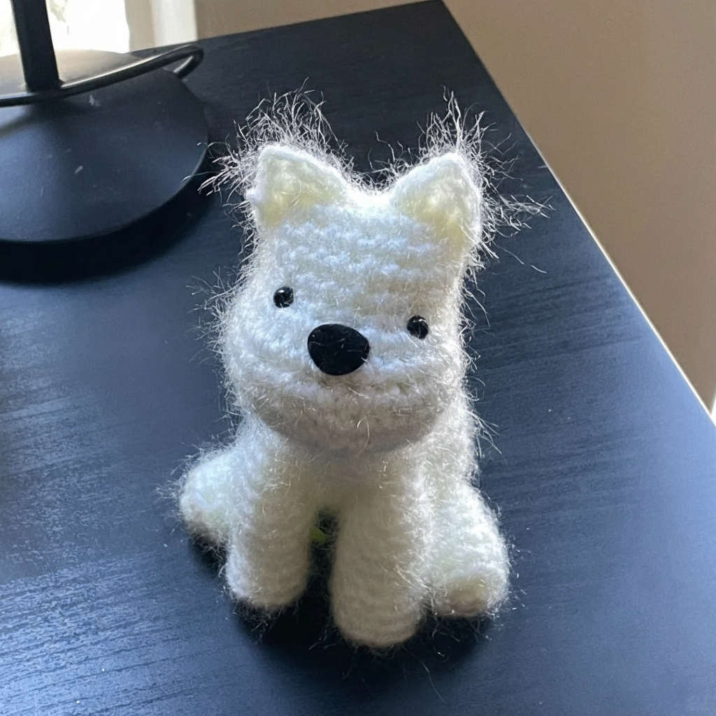White knitted crochet dog toy on a dark surface