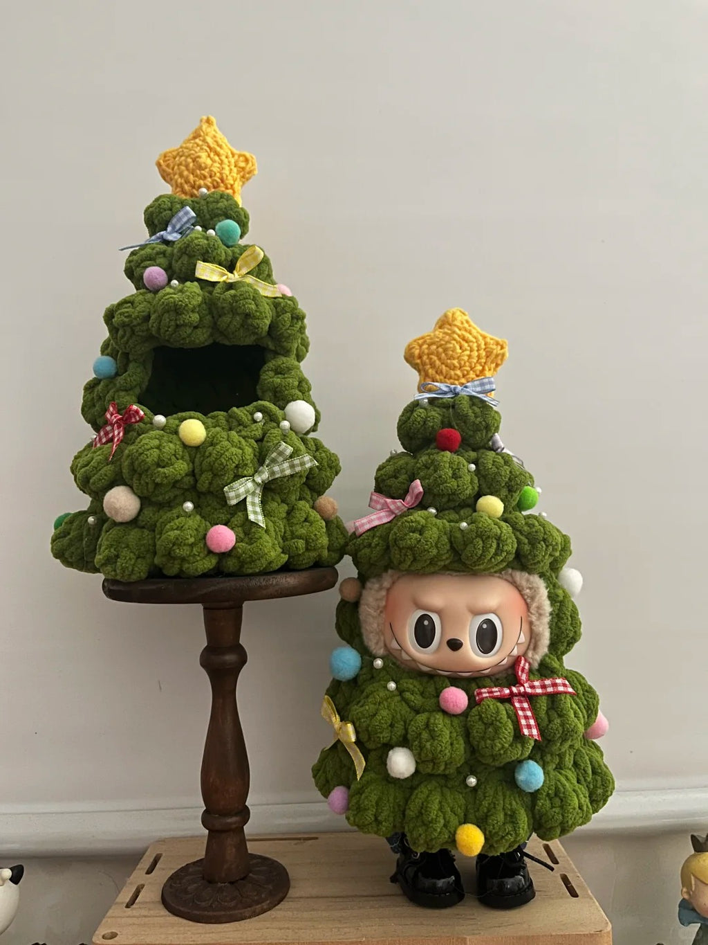 A labubu dressing Christmas Tree Outfit, Two crocheted Christmas trees with decorative elements on a plain background