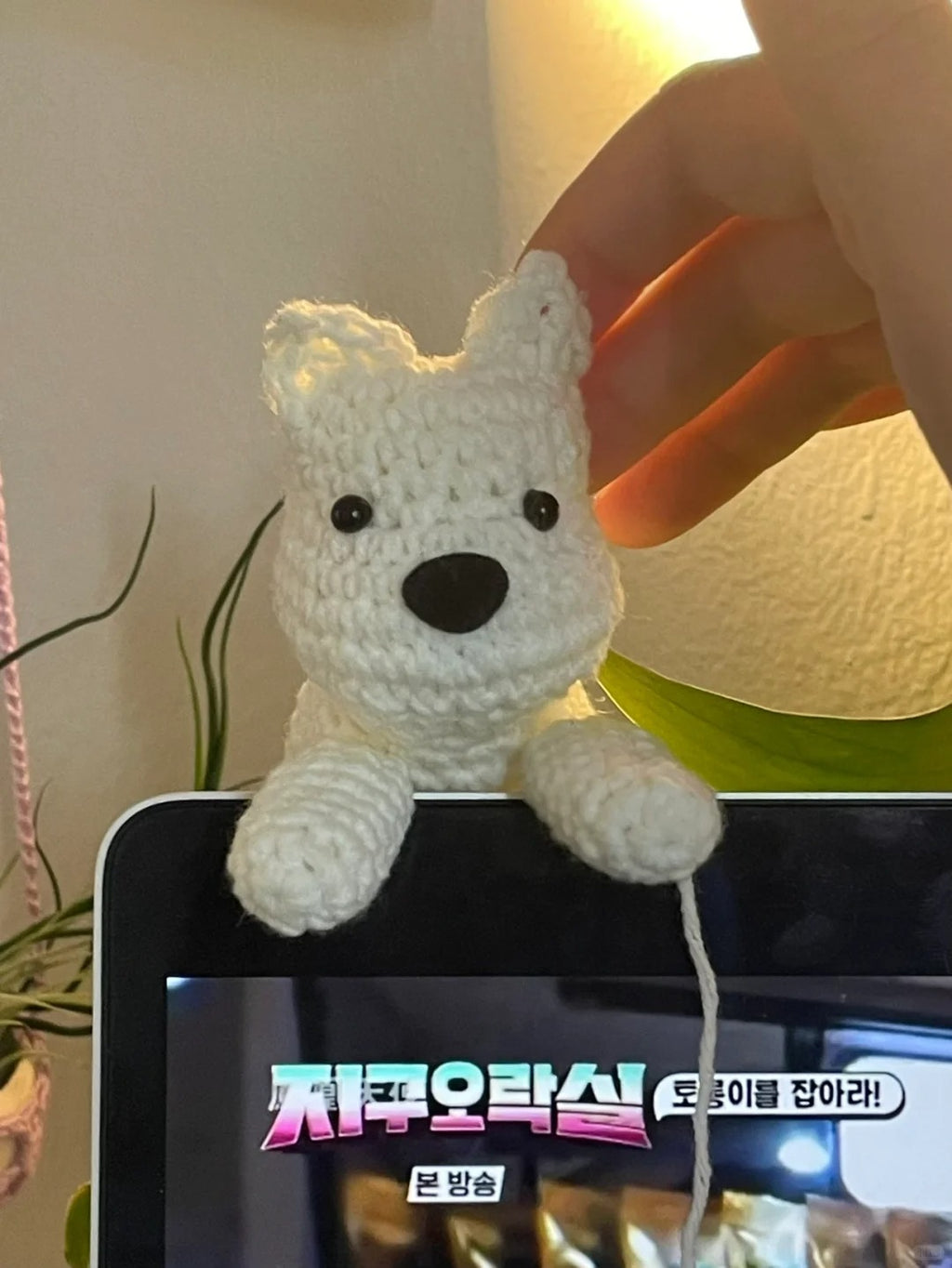 White crochet bear toy on a television screen with a blurred background
