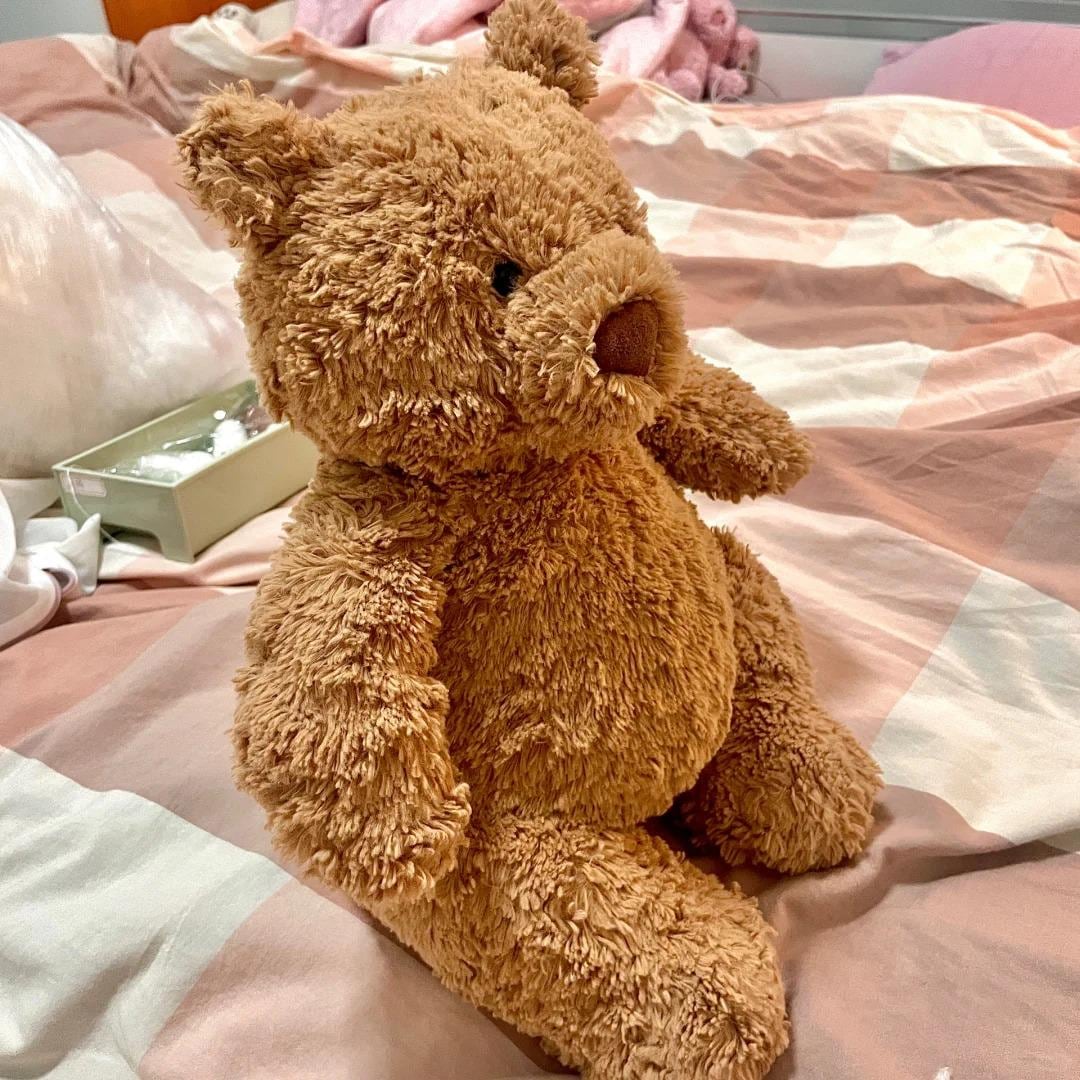 Brown teddy bear on a bed with pink and white bedding