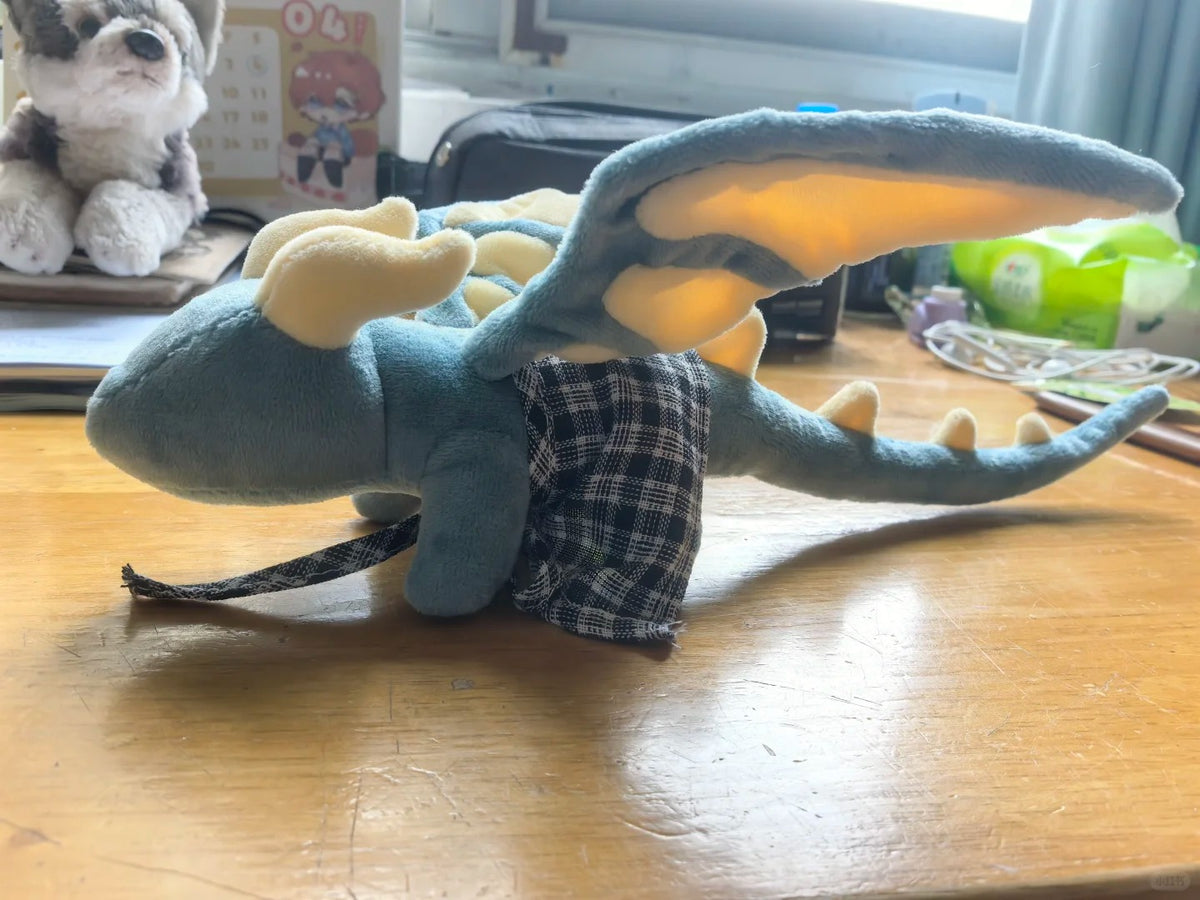Side view of a blue and cream armature dragon plush with raised wing and curved tail