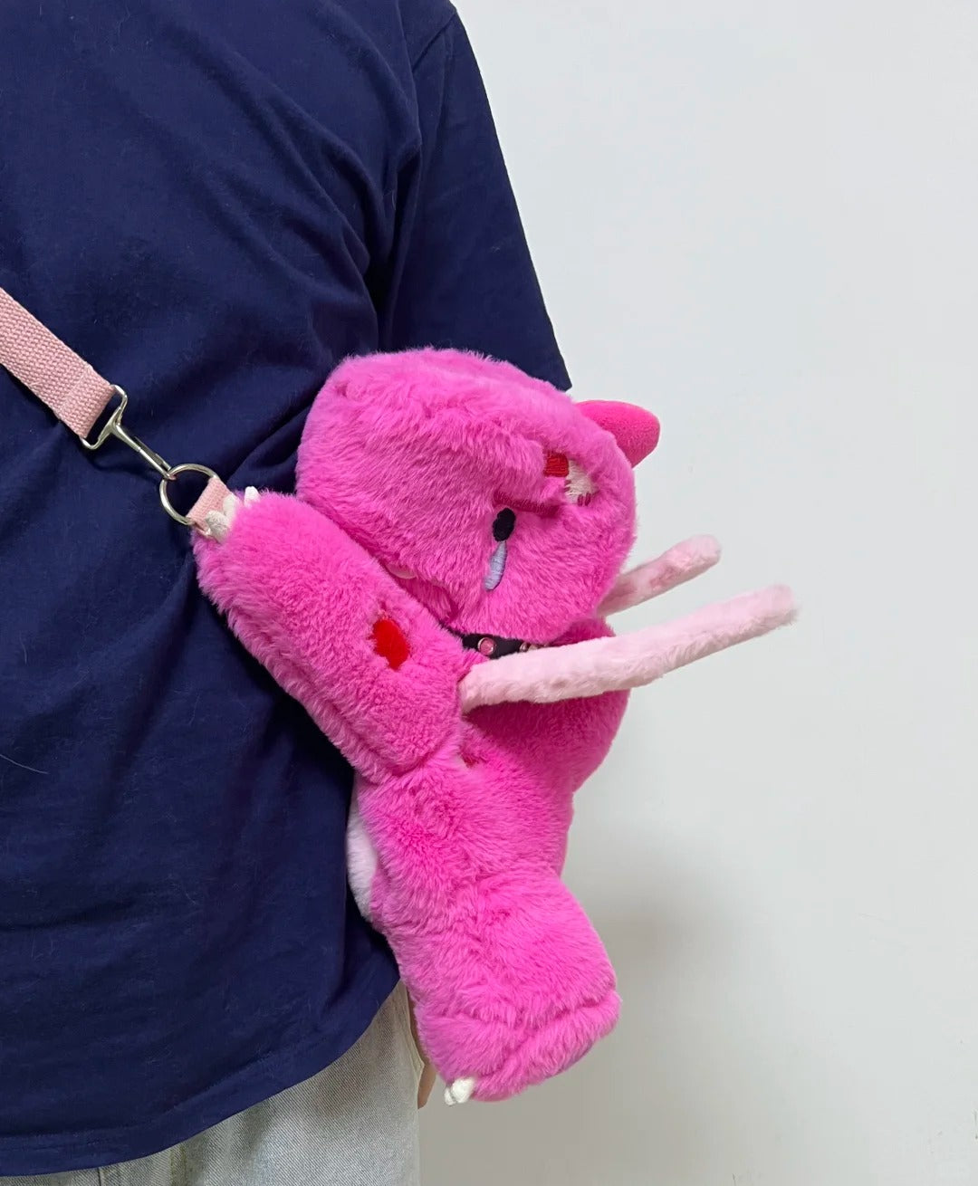 Side view of a pink Boltusk lightning dragon plush with white tusks and soft claws