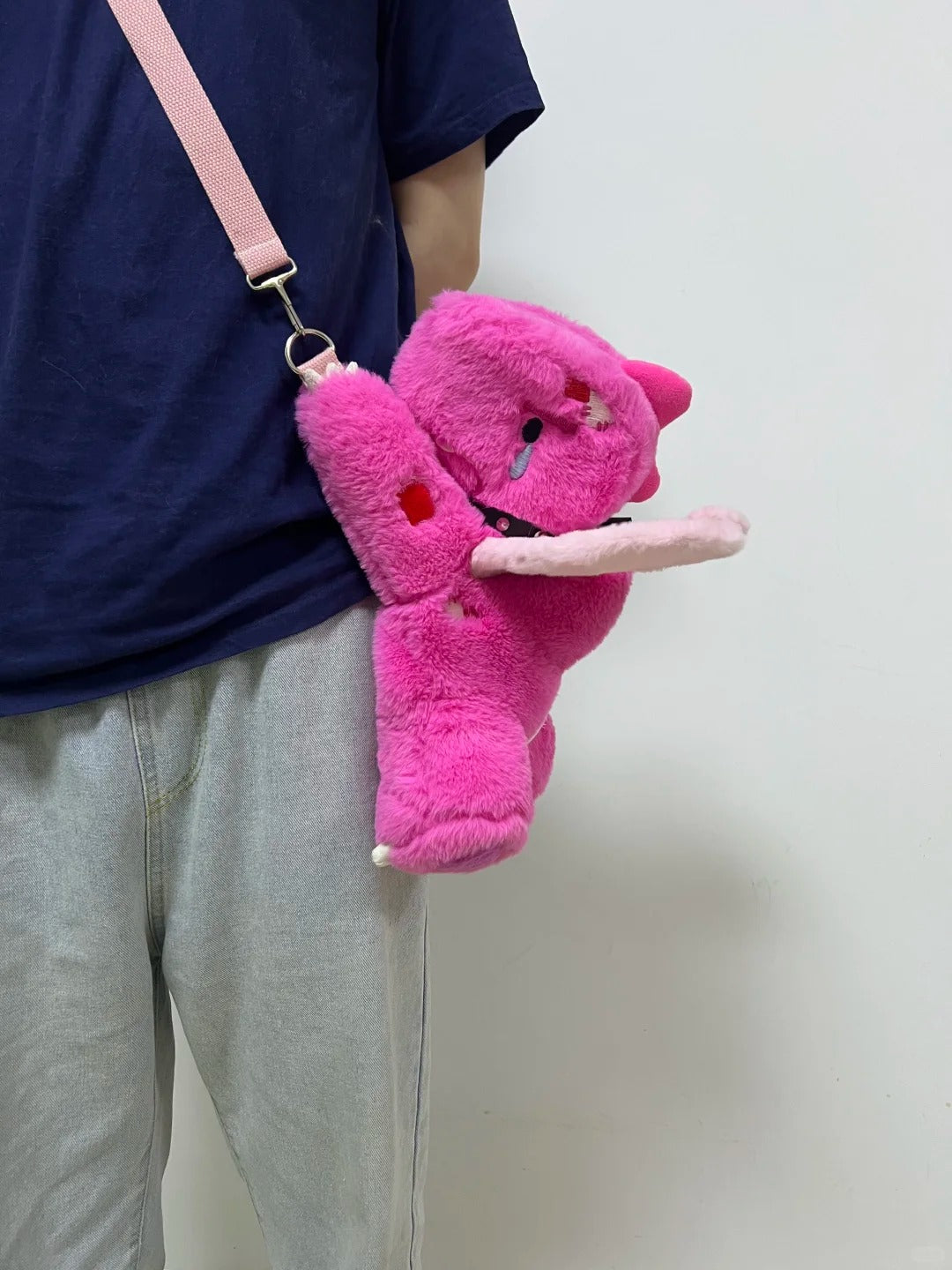 Pink Boltusk dragon plush worn as a shoulder bag with long white tusks