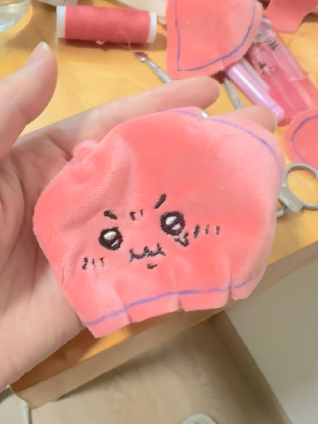 Pink plush face fabric piece with embroidered expression and sewing lines marked