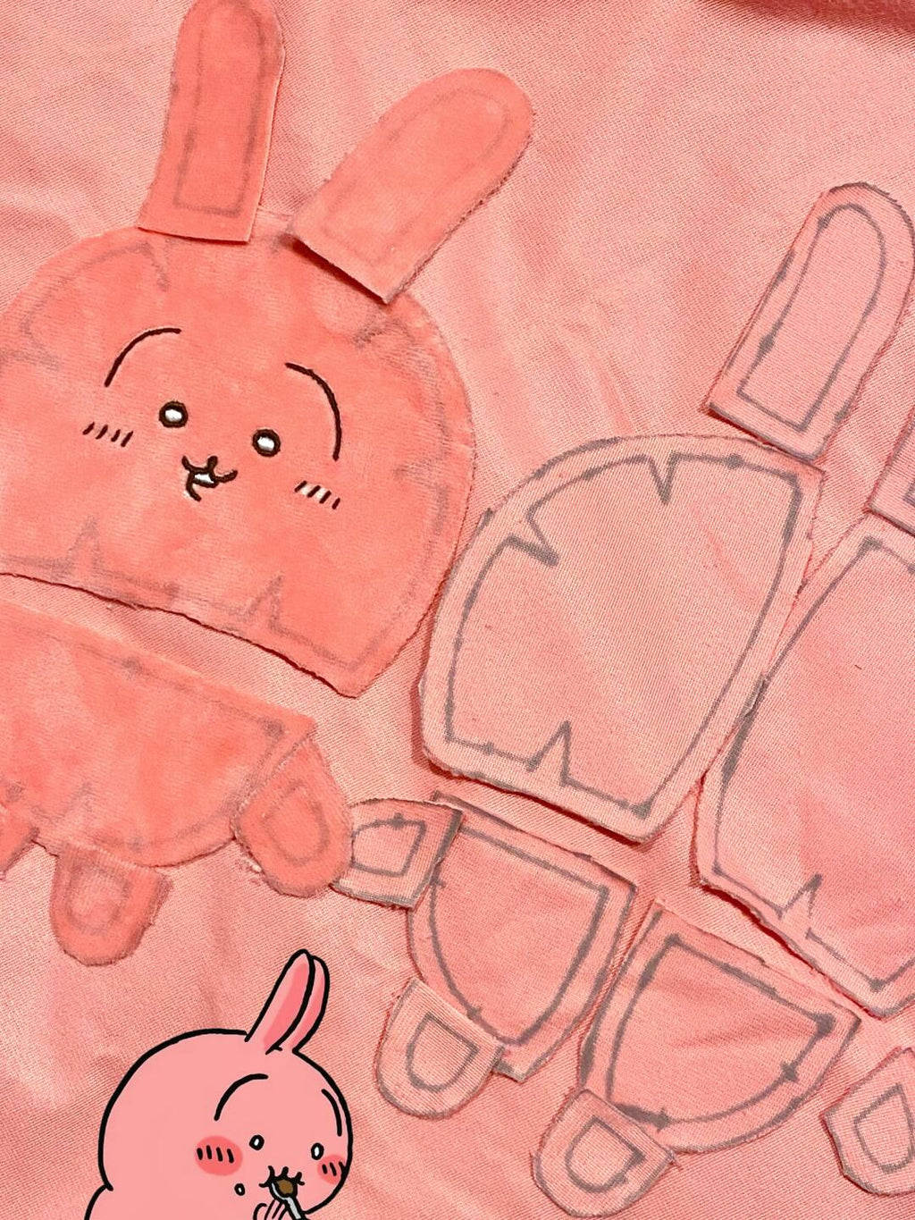 Cut fabric pattern pieces for a pink Chiikawa-inspired full-body plush, including head, ears, body, arms and legs
