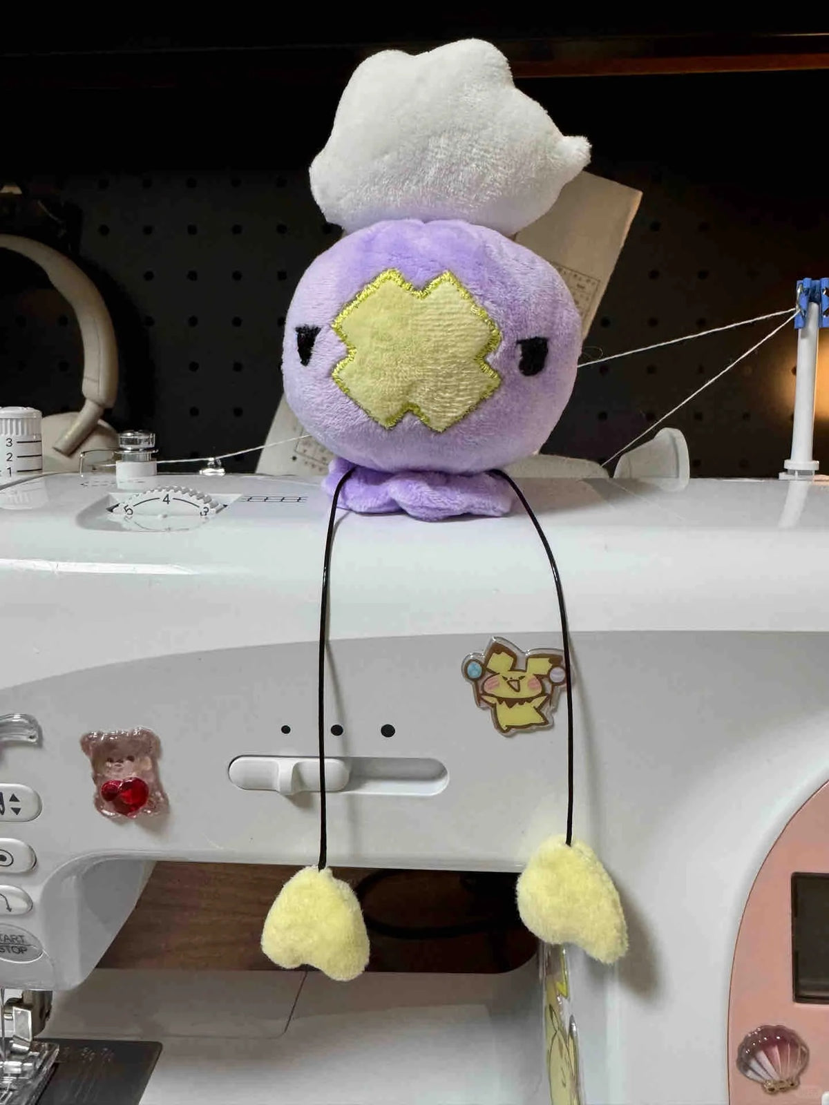 Finished purple Drifloon plush with long heart-tipped cords on a sewing machine