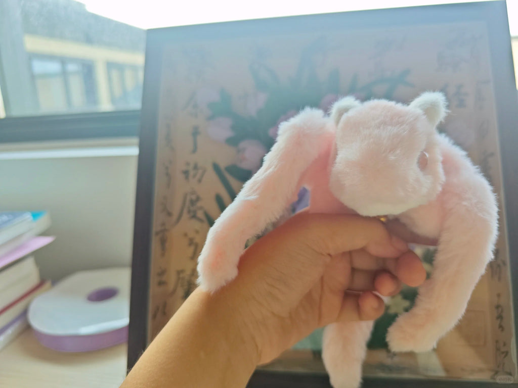 Hand holding a small dragon plush toy in front of a book with floral design