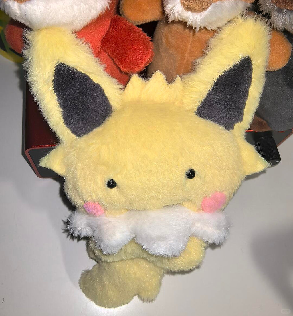 Handmade Eeveelution plush sewn from the pattern, showing a small yellow Jolteon-style plush with black ears, pink cheeks, and a white fluffy chest
