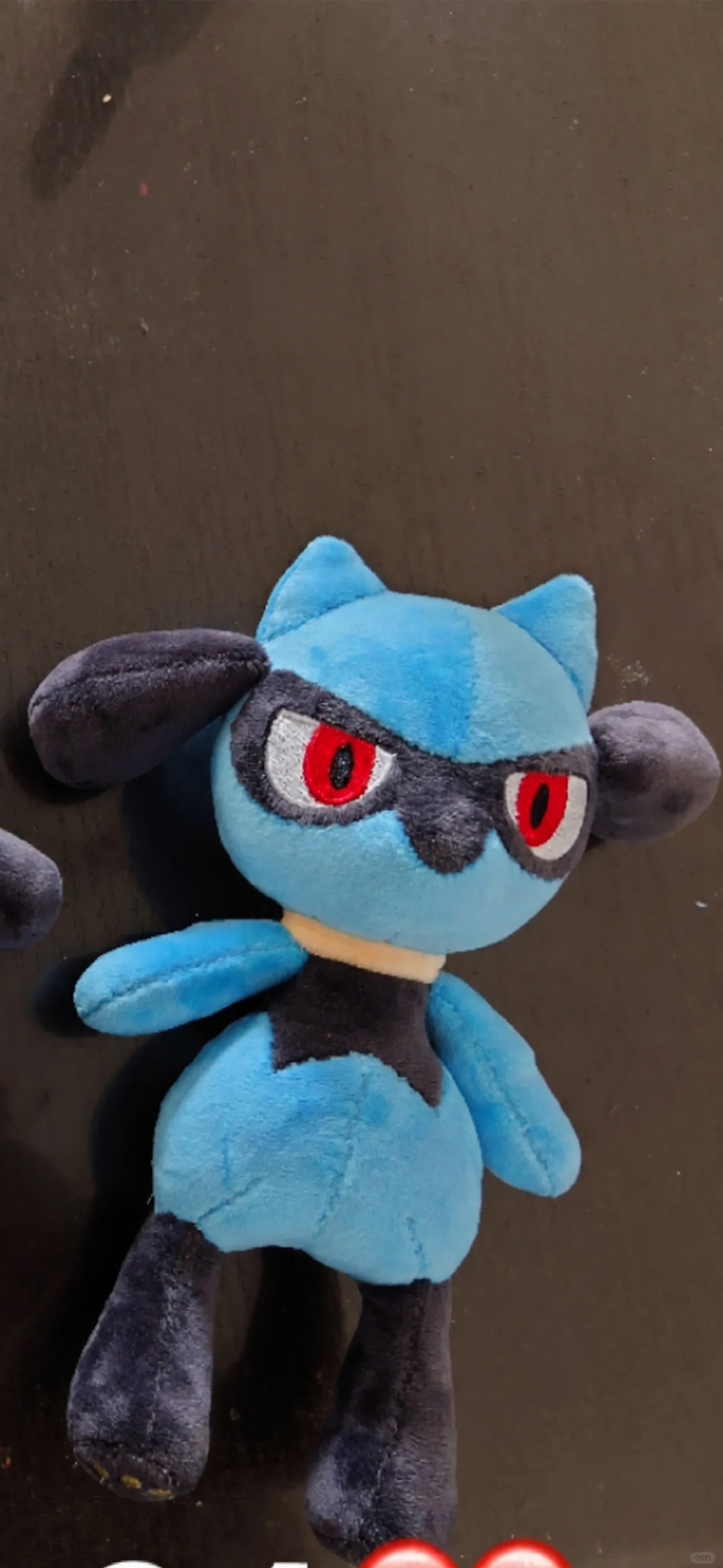 Lucario-inspired plush photographed from above, showing the finished face, ears, body and long dark legs