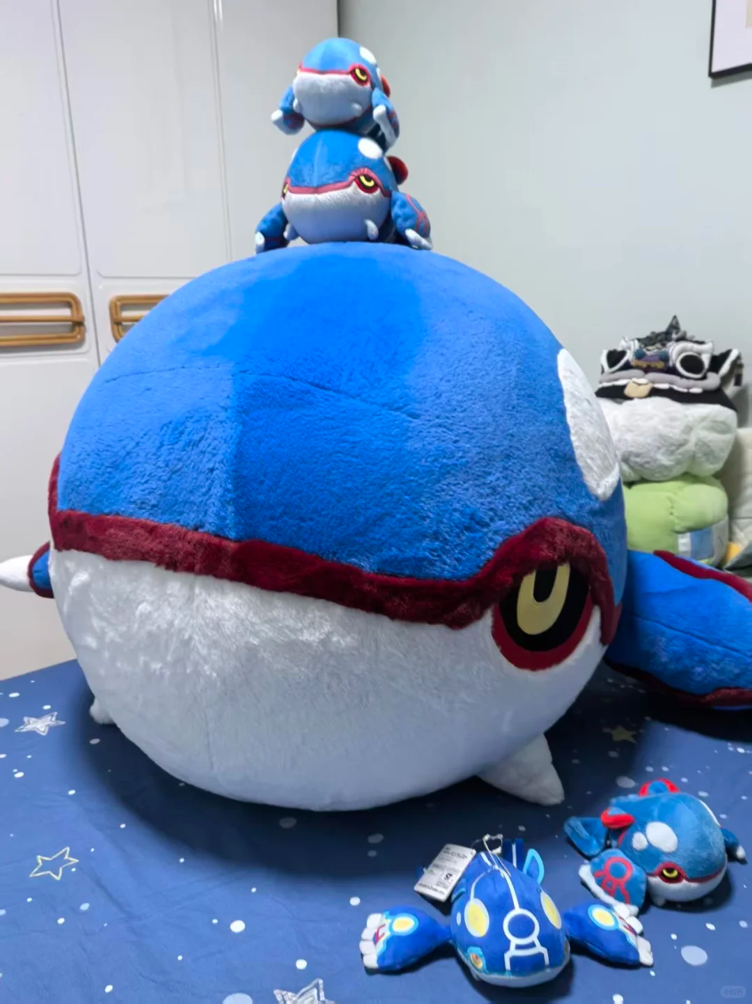 Giant blue Kyogre plush displayed with miniature and keychain-sized Kyogre plushies